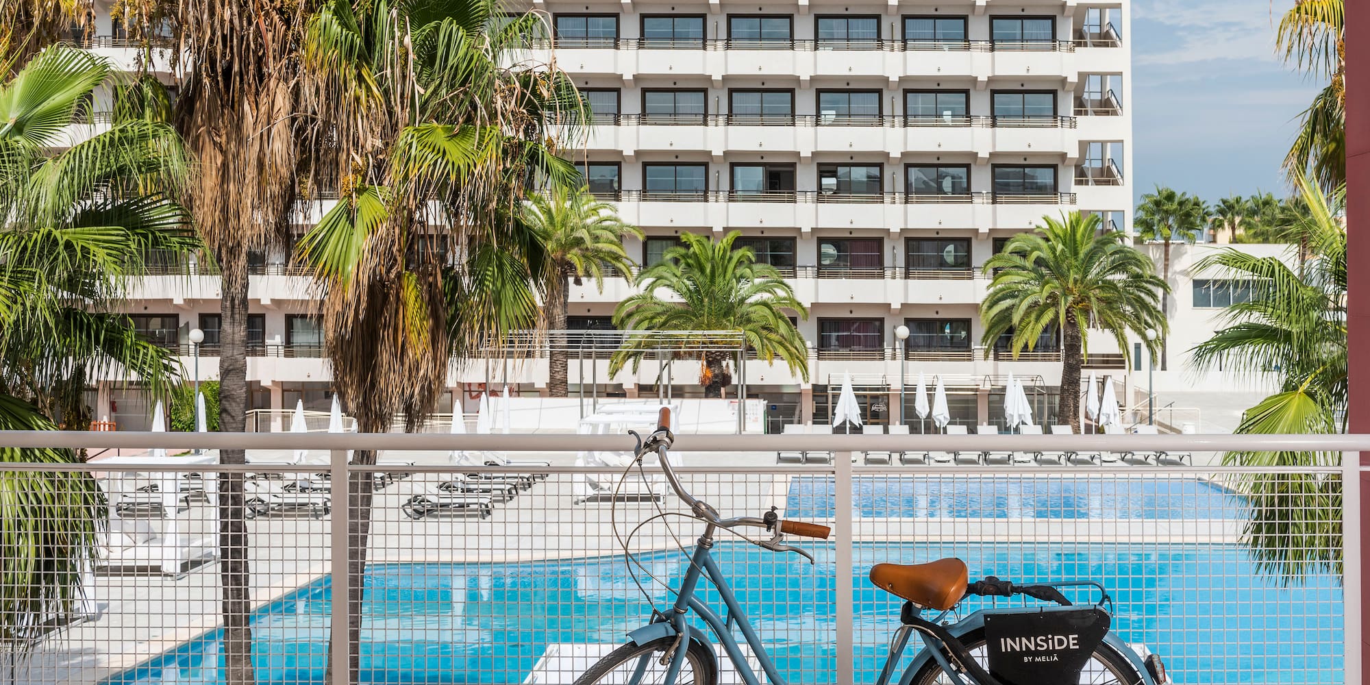a bicycle leaning against a fence with a pool in the background