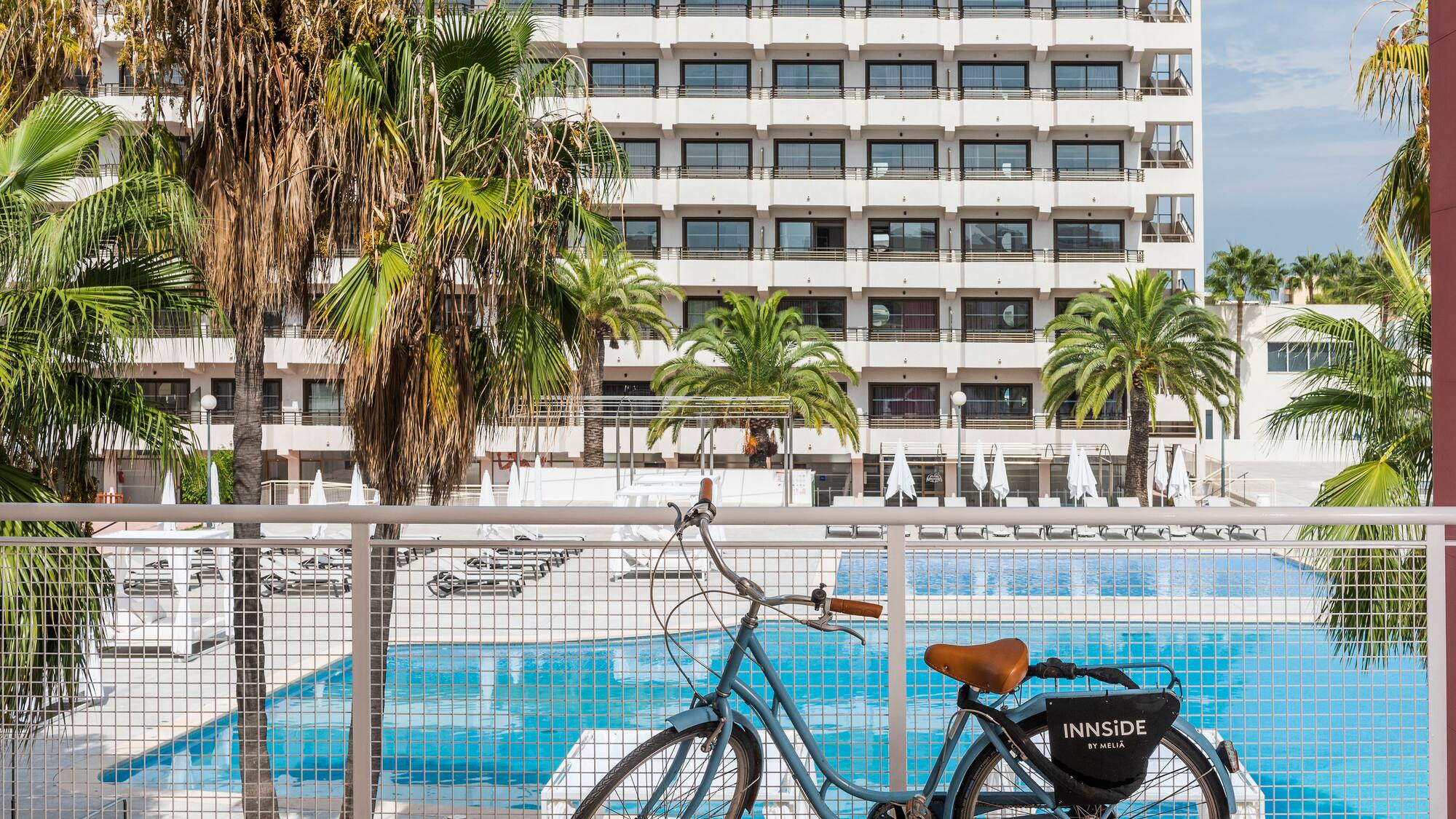 a bicycle leaning against a fence with a pool in the background