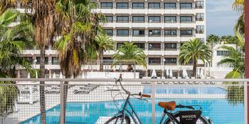 a bicycle leaning against a fence with a pool in the background