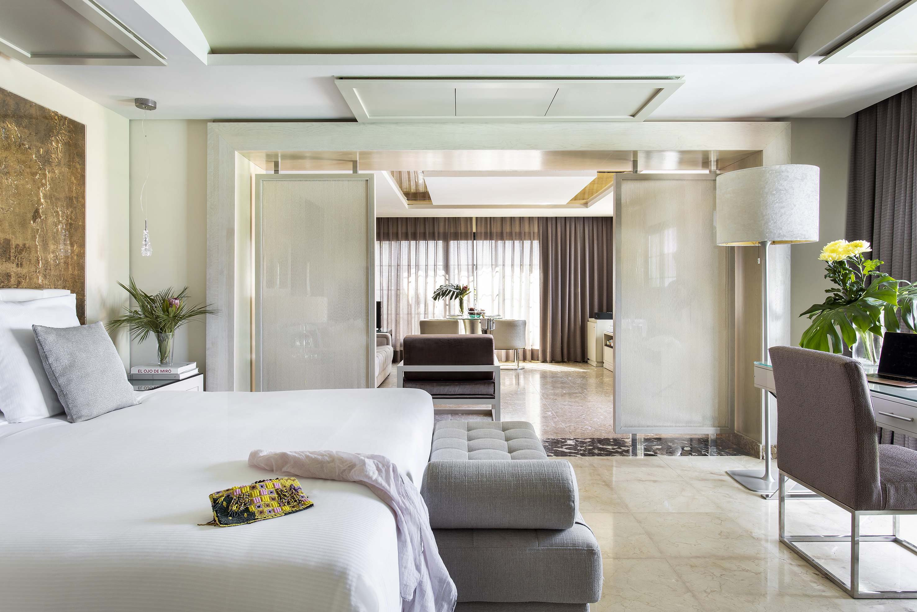 Luxury hotel bedroom suite with white bed and modern living area.