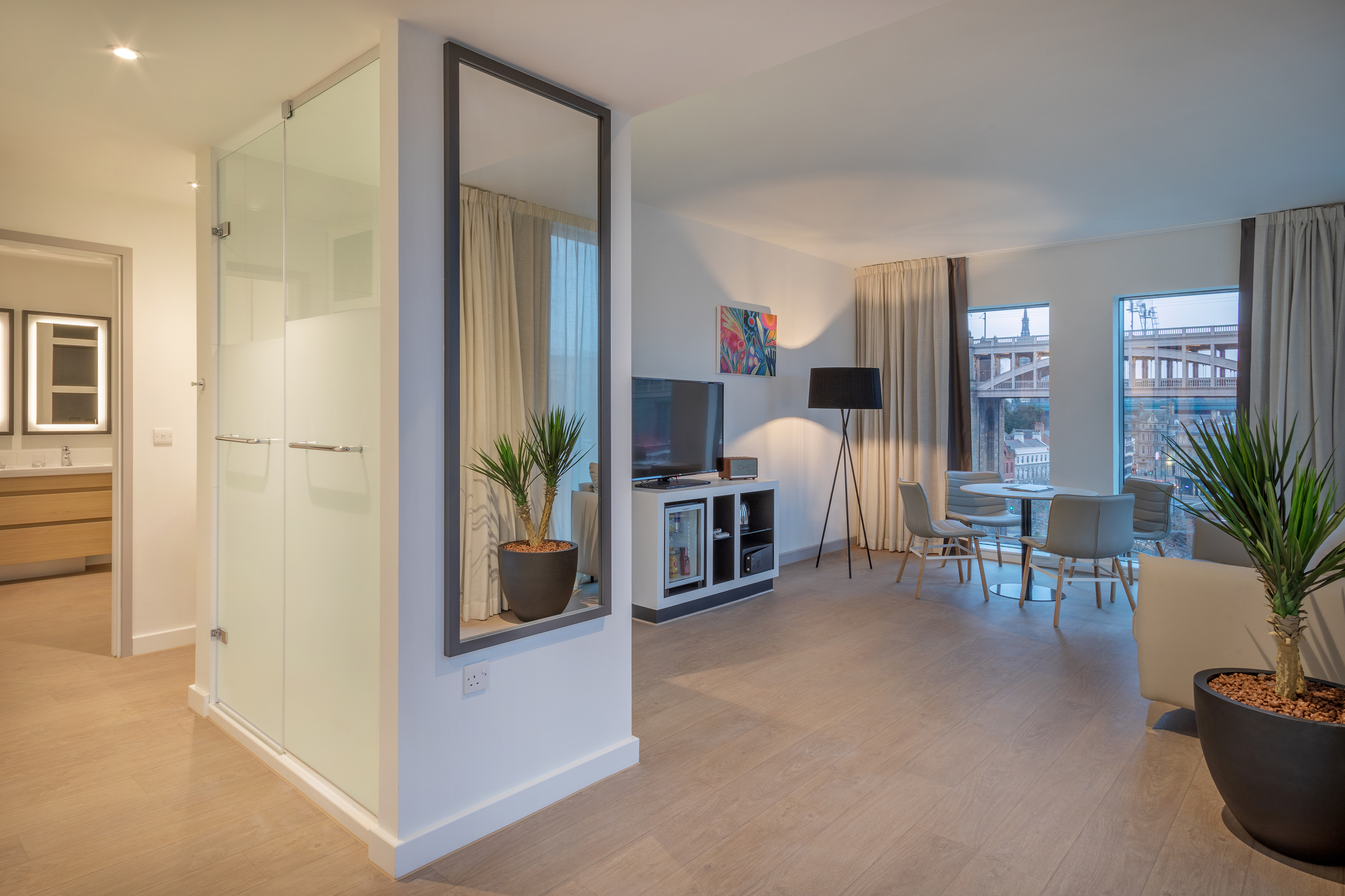 Modern studio apartment with living and dining, glass shower, and city view.