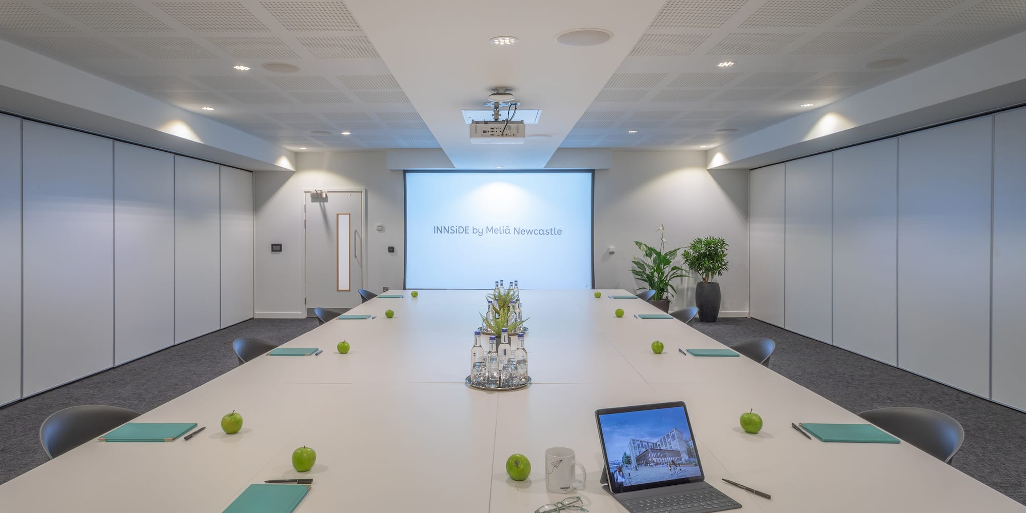 a conference room with a laptop and green apples on a table