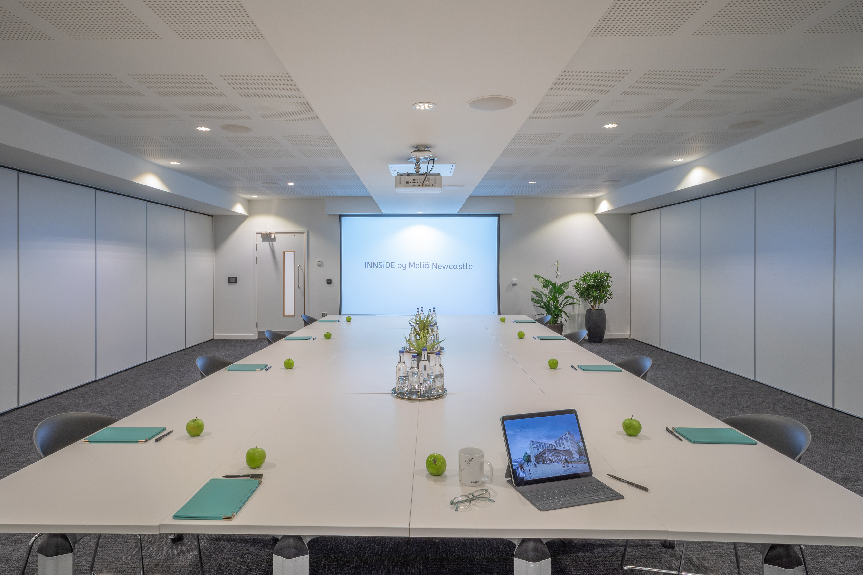 a conference room with a laptop and green apples on a table