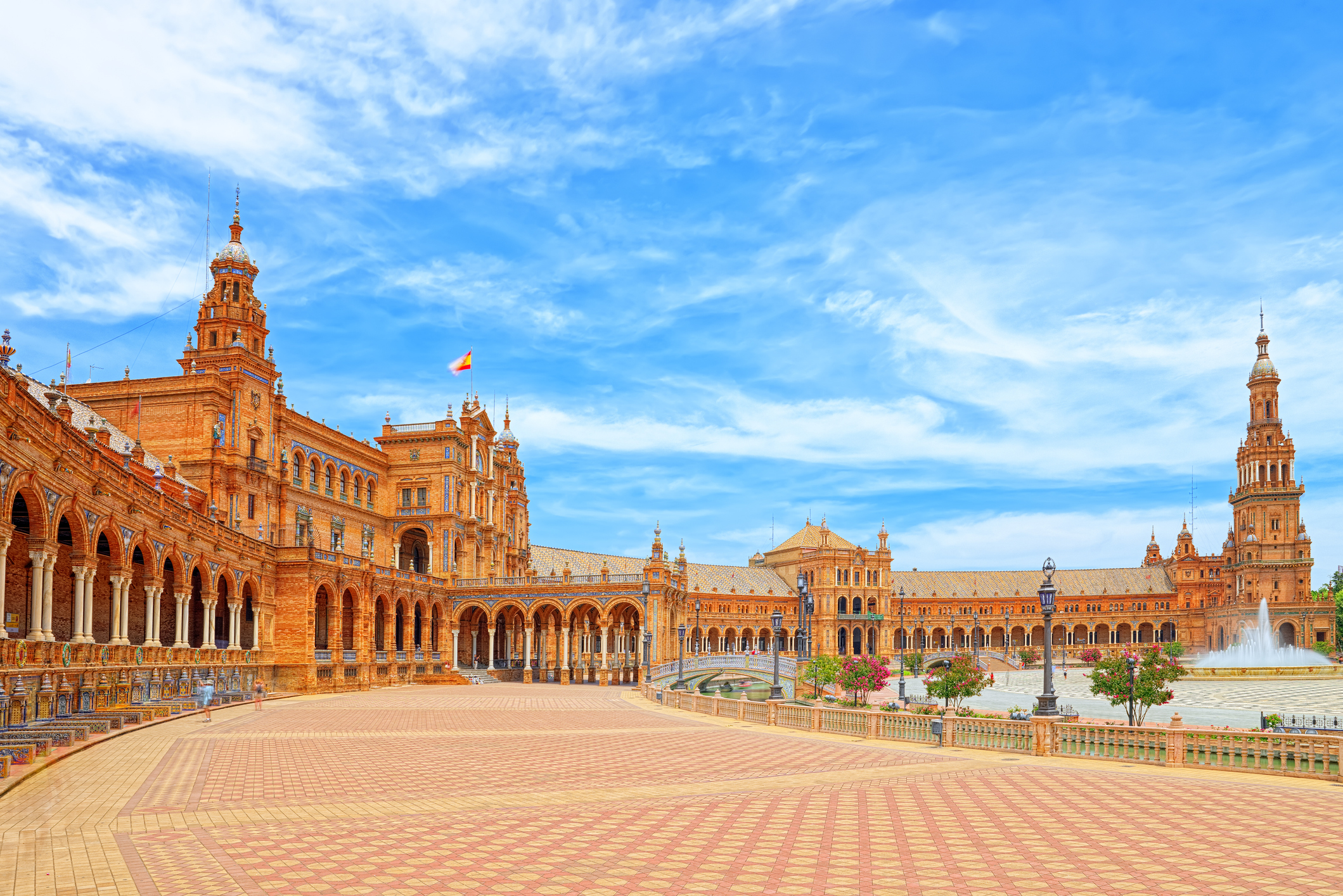 Seville's Plaza de España, featuring ornate brick buildings, towers, and large square.