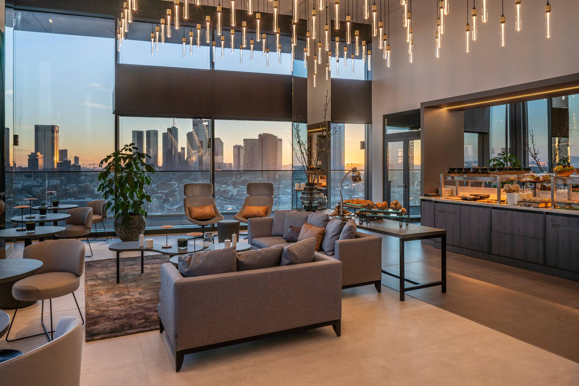 Modern lounge with city skyline sunset view, contemporary lighting, and buffet.