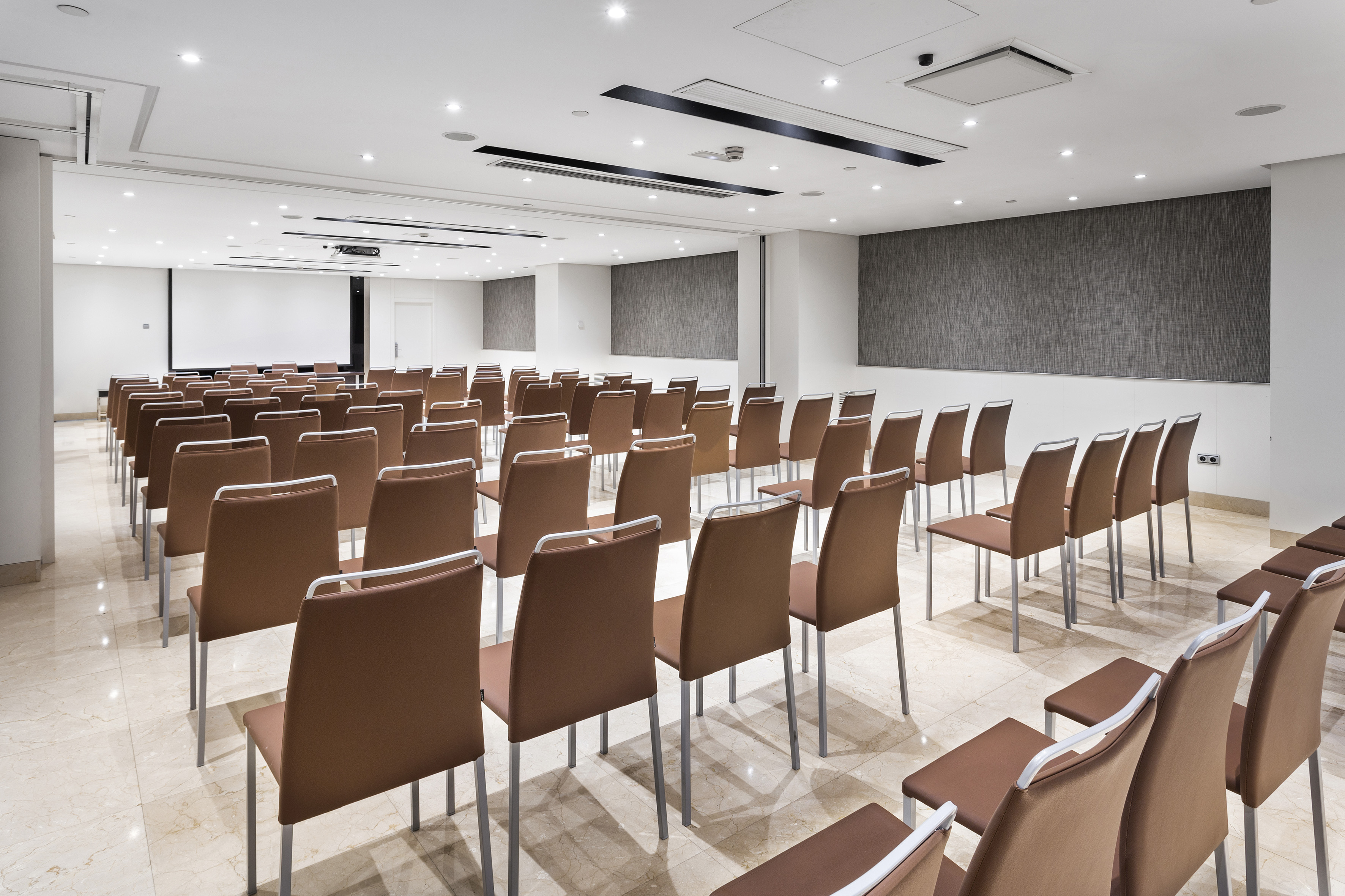 Empty modern conference room with brown chairs and a projection screen.