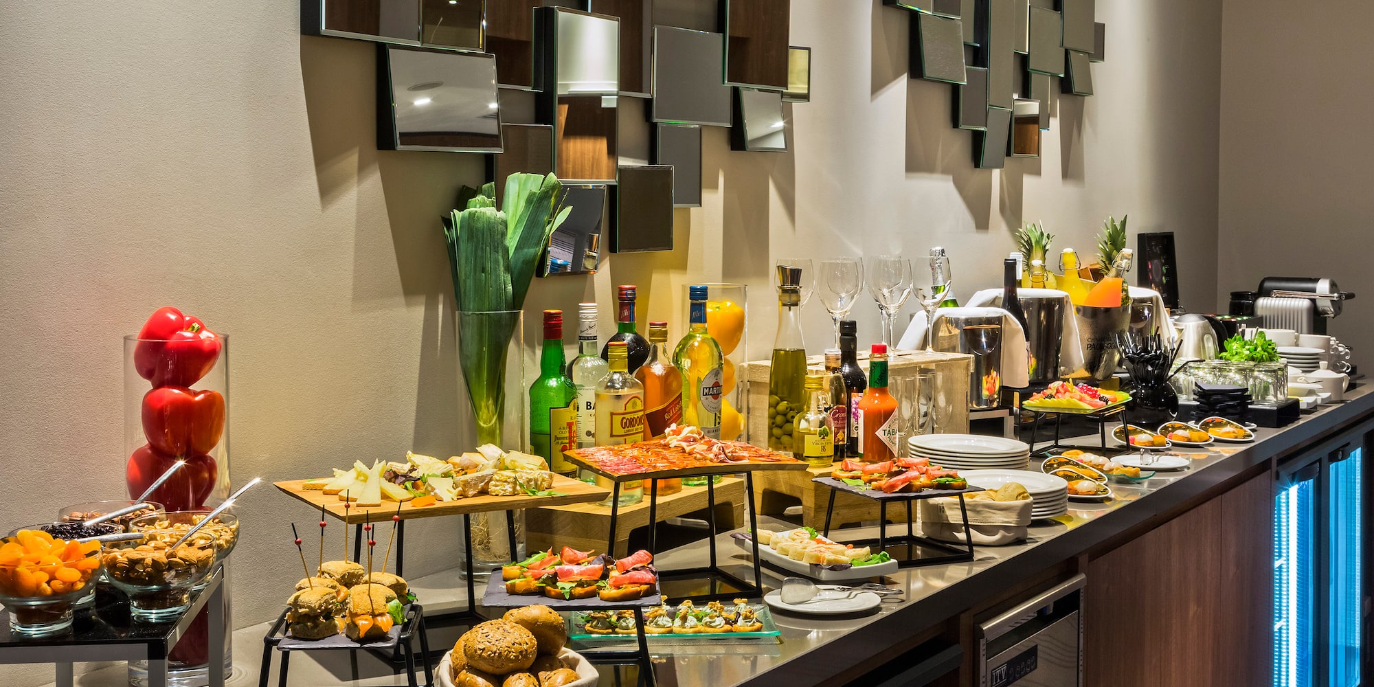 Hotel buffet spread with appetizers, cold cuts, cheeses, bread, and drinks.