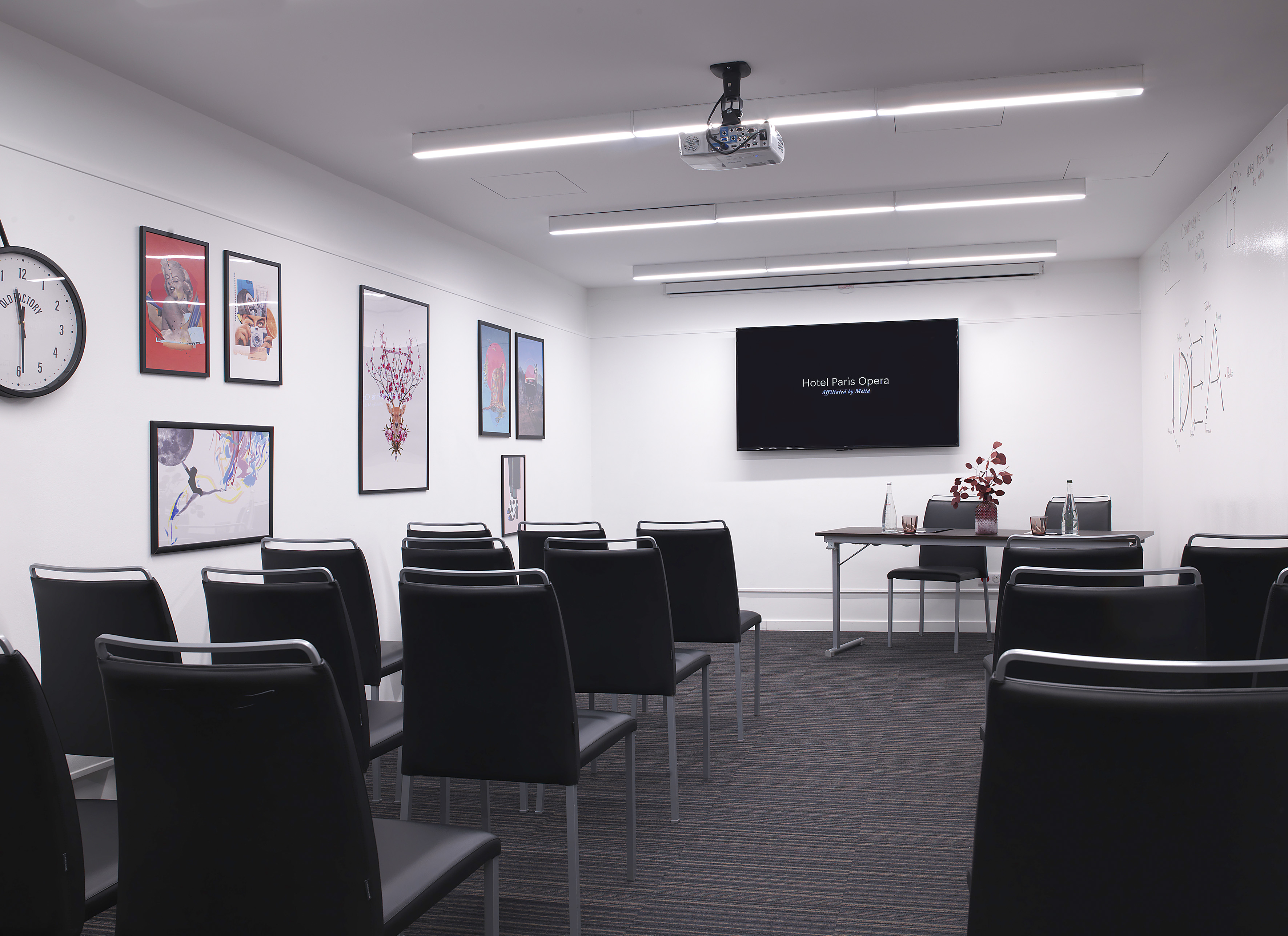 Modern meeting room at Hotel Paris Opera with black chairs, TV screen, and modern art.