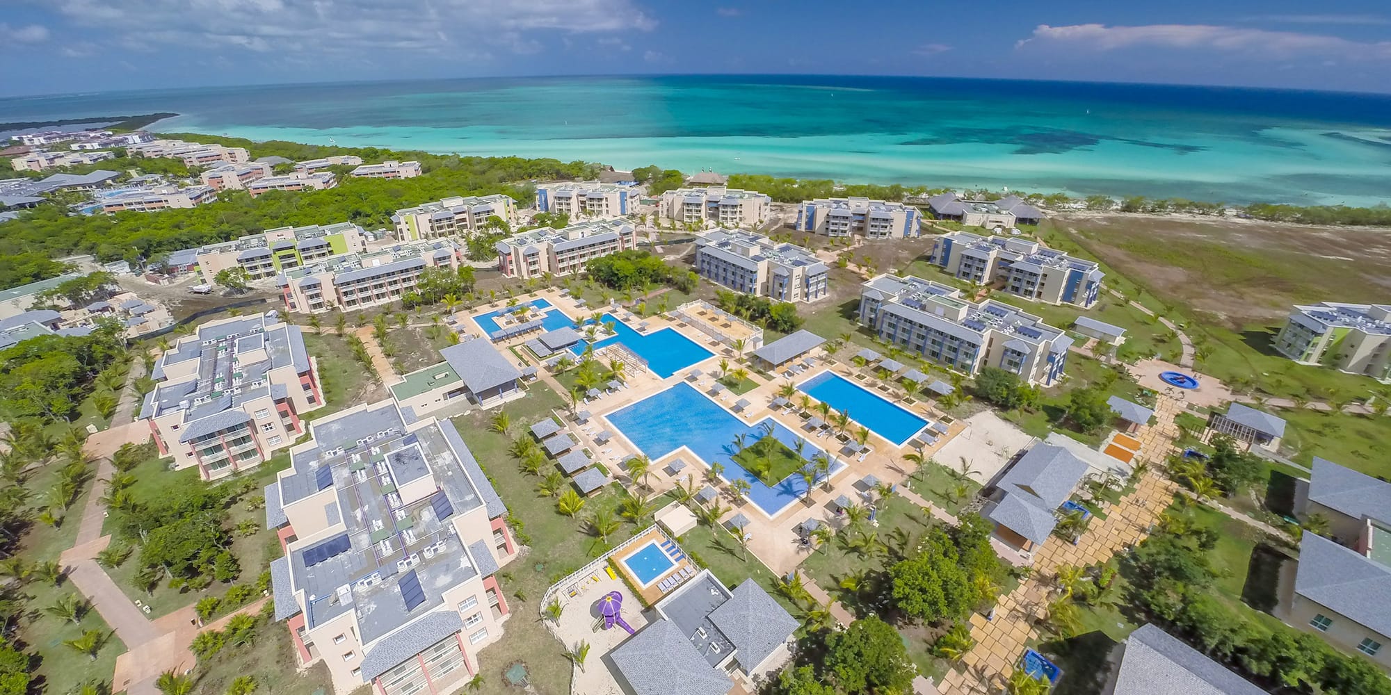 a group of buildings with a pool and trees by the water