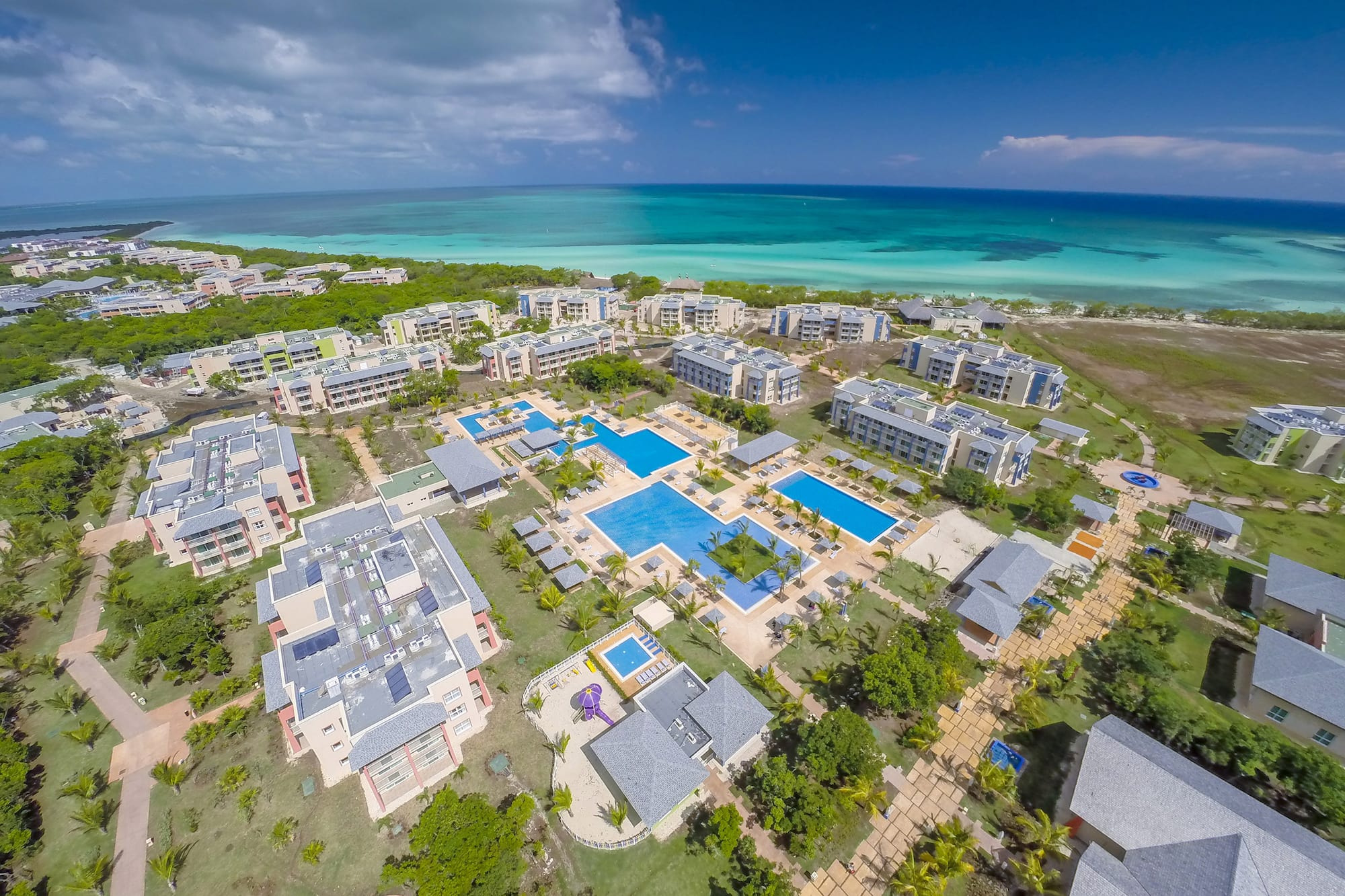 a group of buildings with a pool and trees by the water