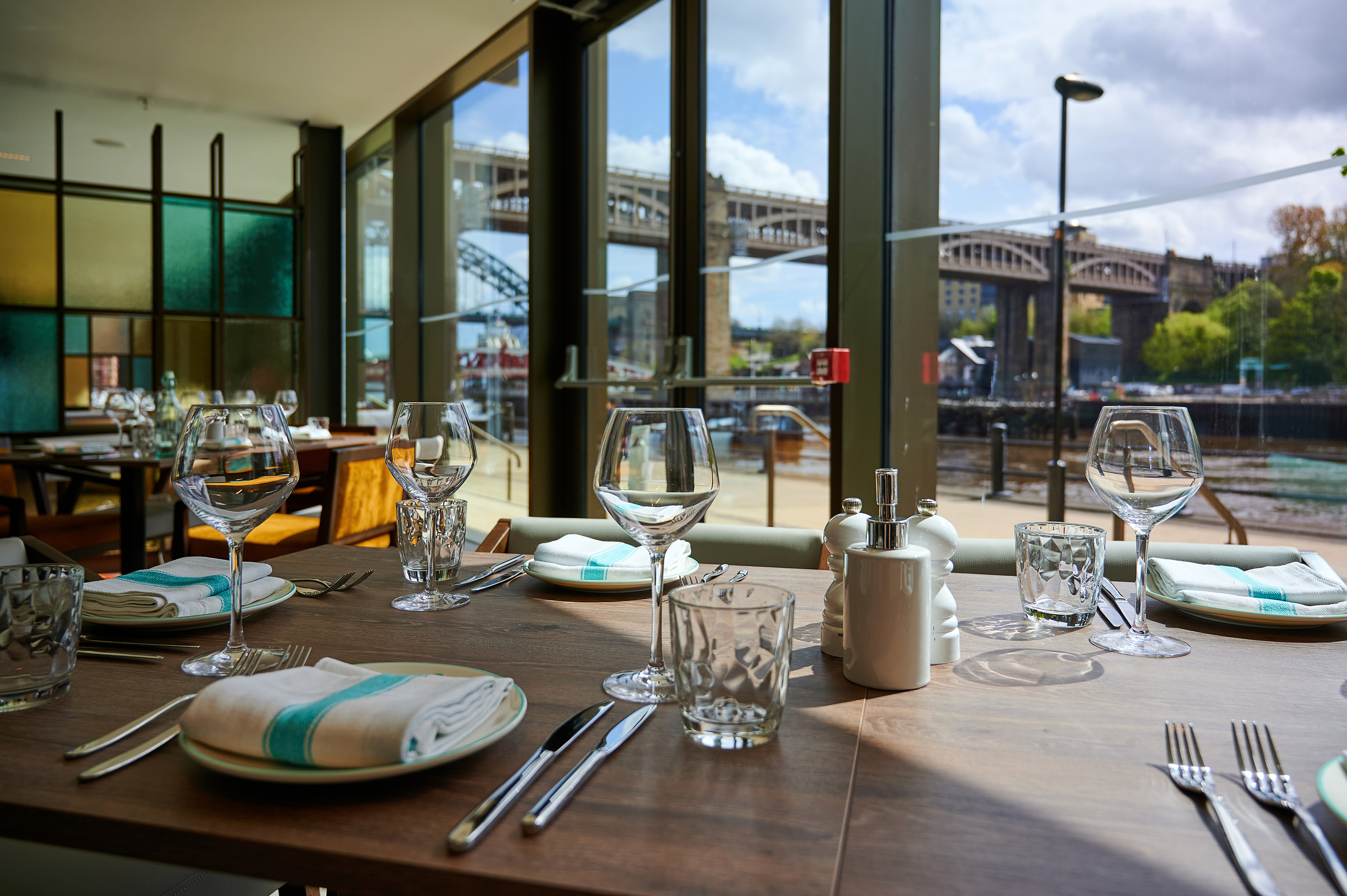 Restaurant dining table with Newcastle bridge and river view through windows.