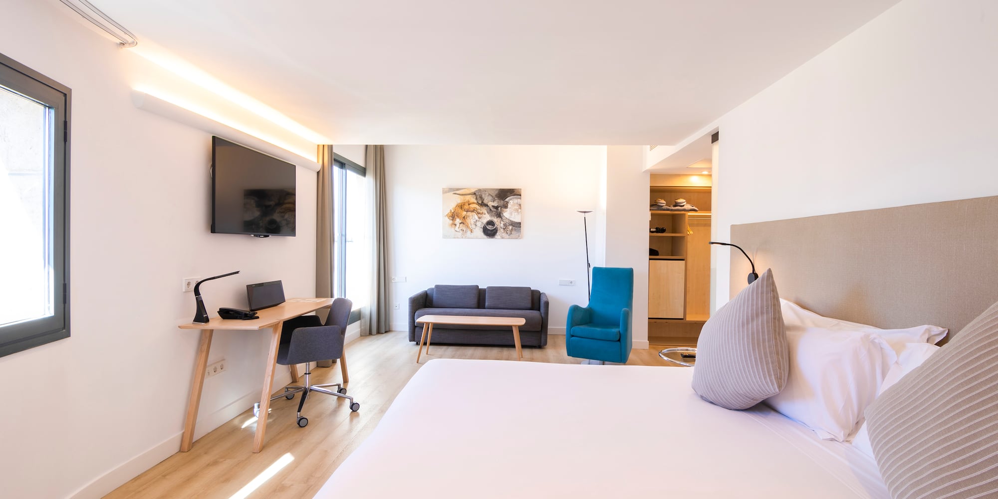 a room with a bed and a desk and a tv