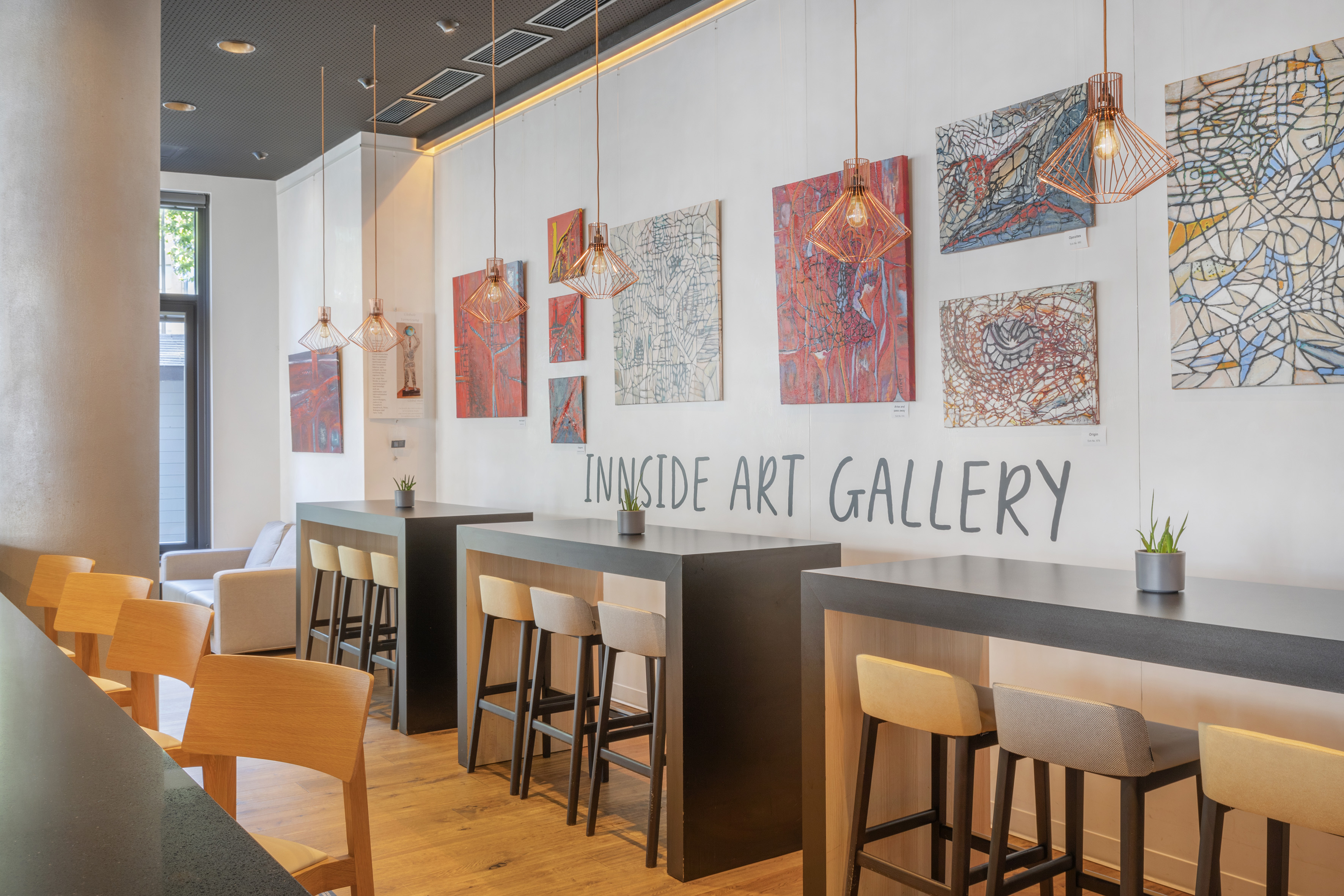 INNSIDE Art Gallery with modern art paintings, high tables, and bar stools.