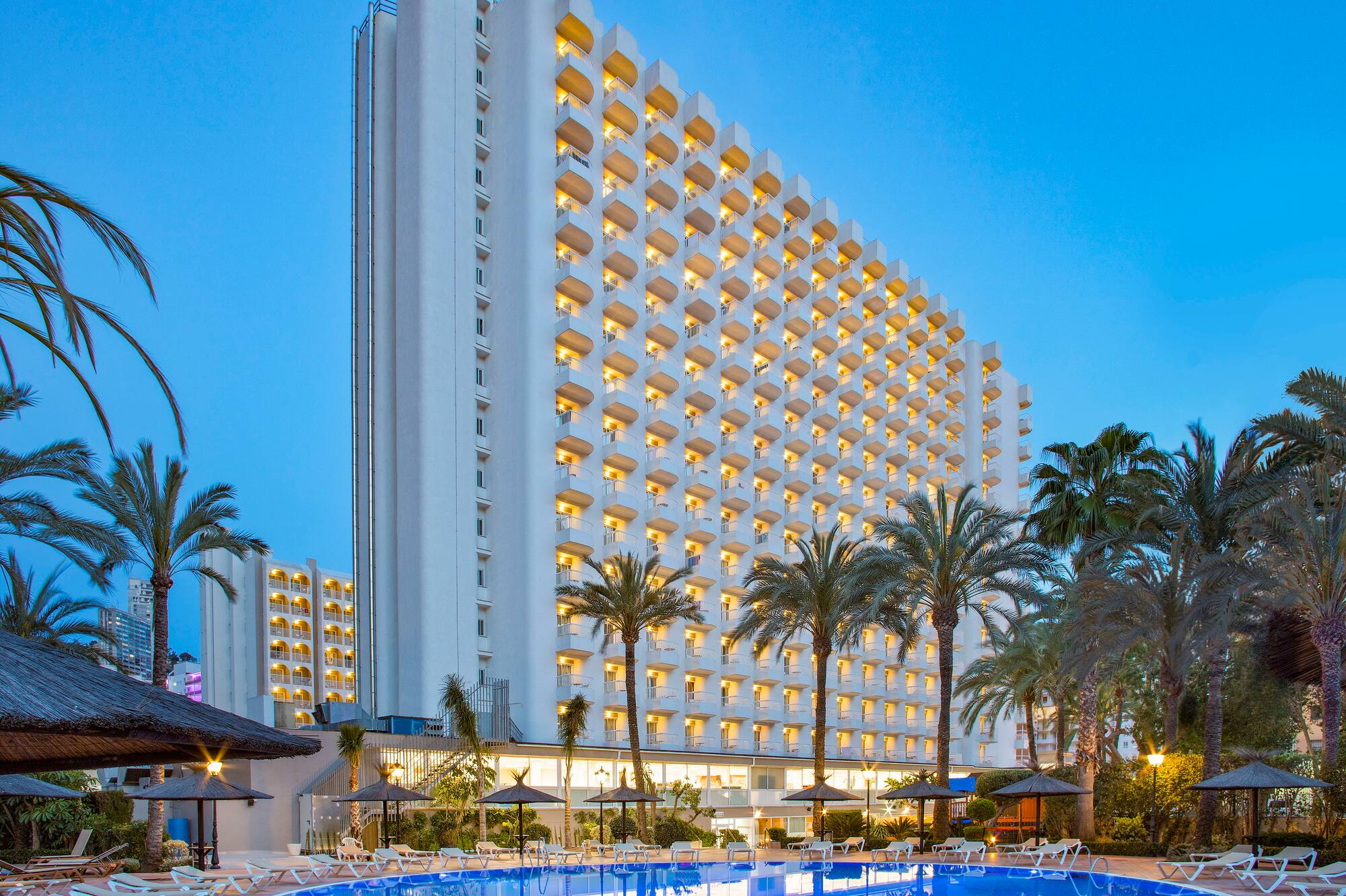 a large building with a pool and palm trees