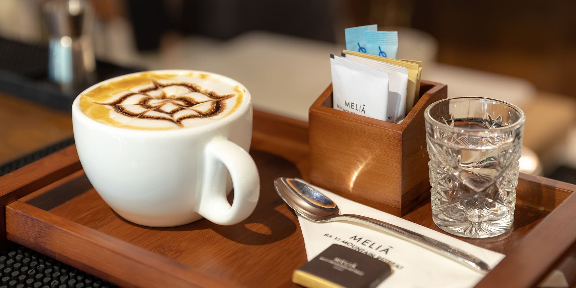 a cup of coffee with a design on the foam and a glass of water