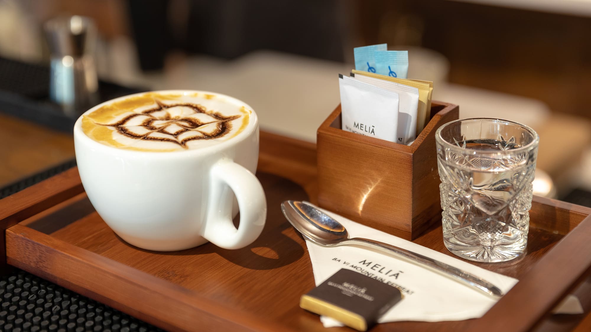 a cup of coffee with a design on the foam and a glass of water