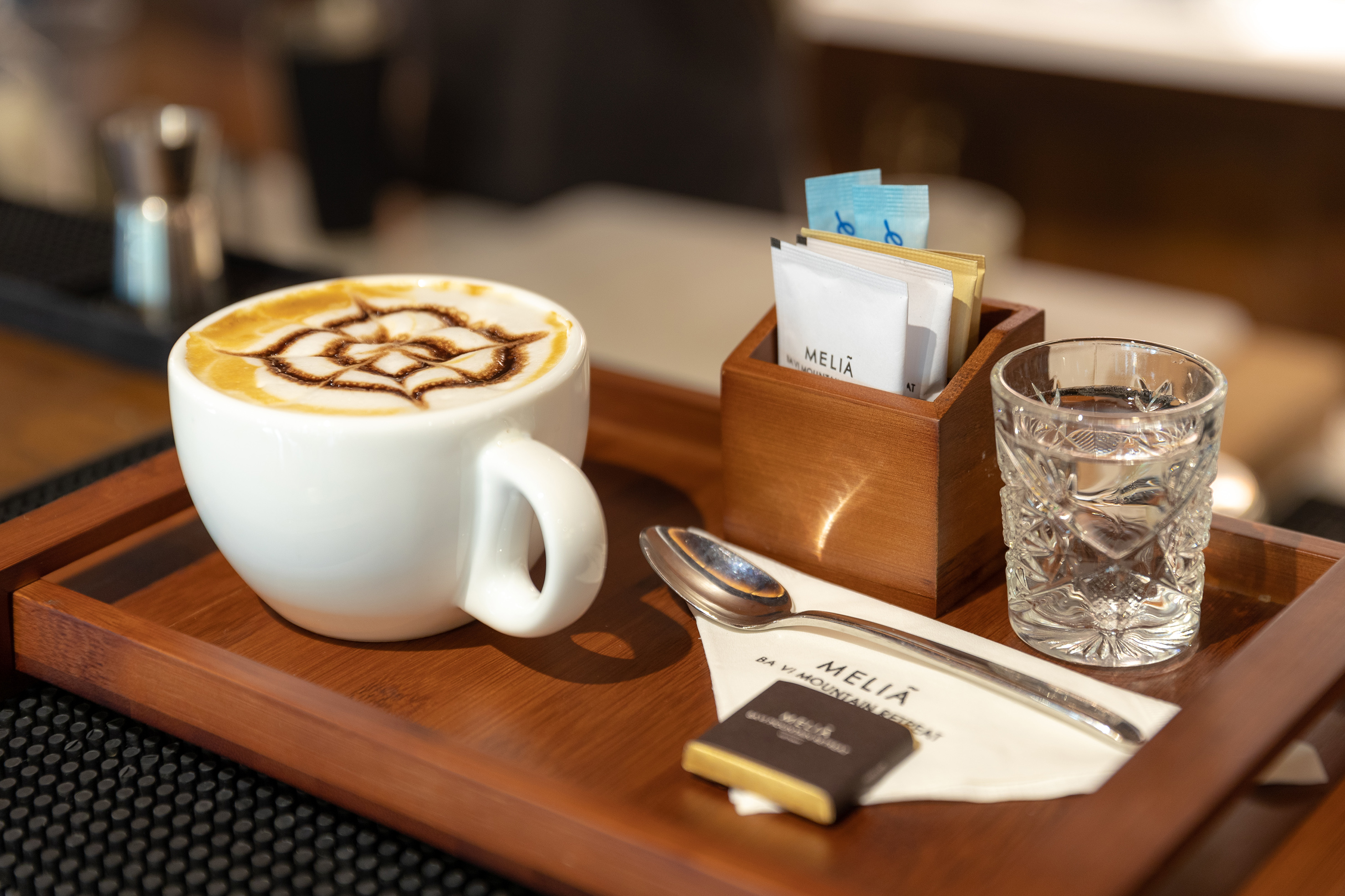 a cup of coffee with a design on the foam and a glass of water