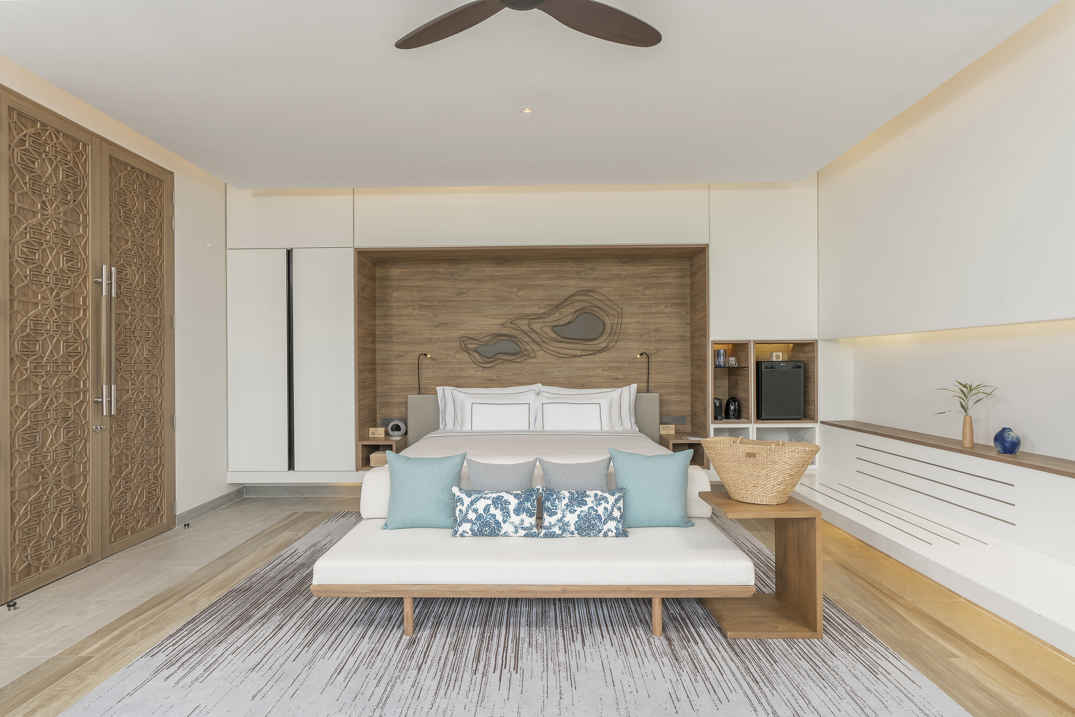 Elegant resort bedroom with carved wood doors, king bed, and stylish daybed.