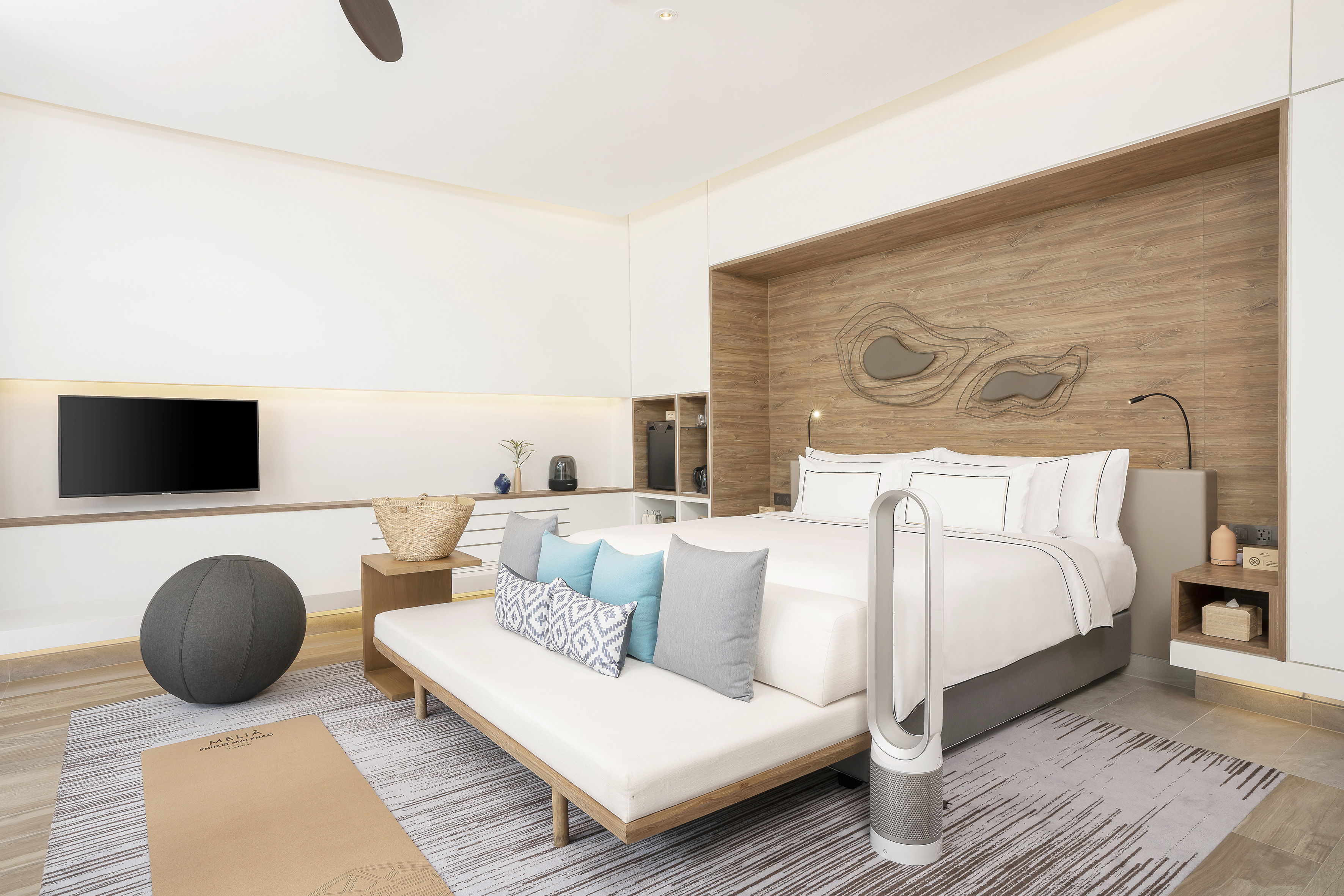 Bright hotel bedroom with king bed, yoga mat, exercise ball, and TV.
