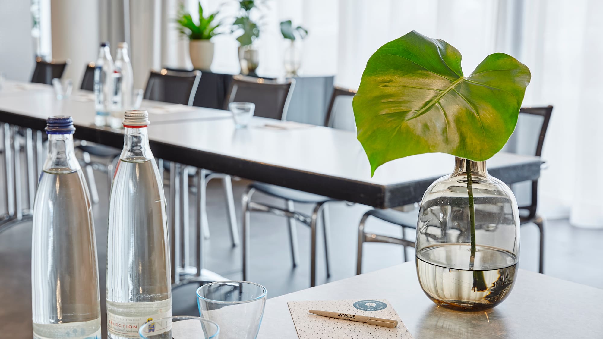 a table with a glass vase and a green leaf in it