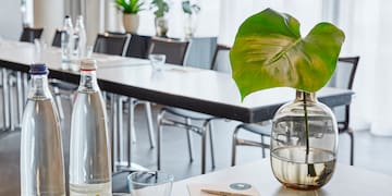 a table with a glass vase and a green leaf in it