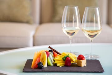 a plate of fruit and a couple wine glasses on a table