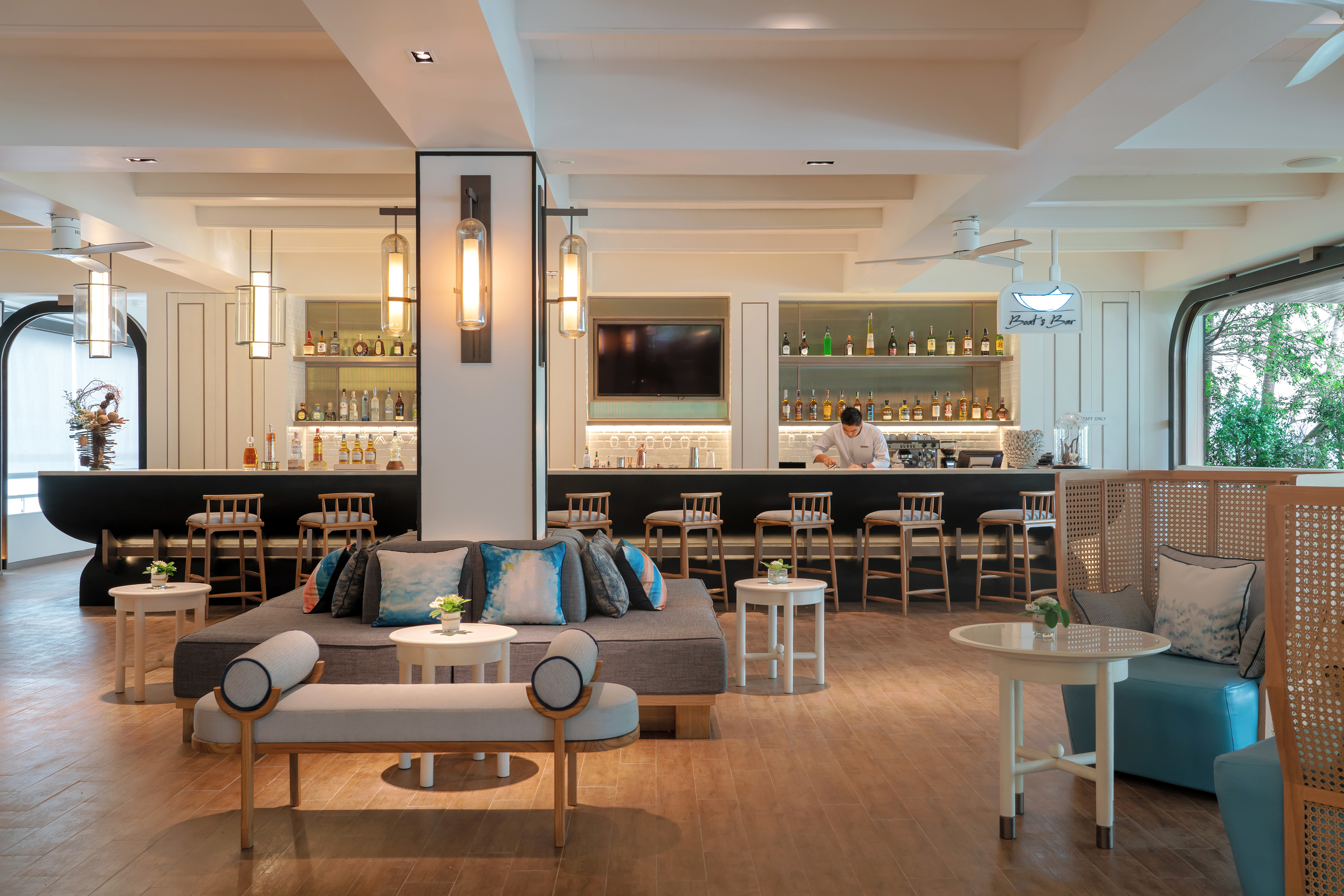 Modern hotel bar lounge with bartender, comfortable seating areas, and sleek design.