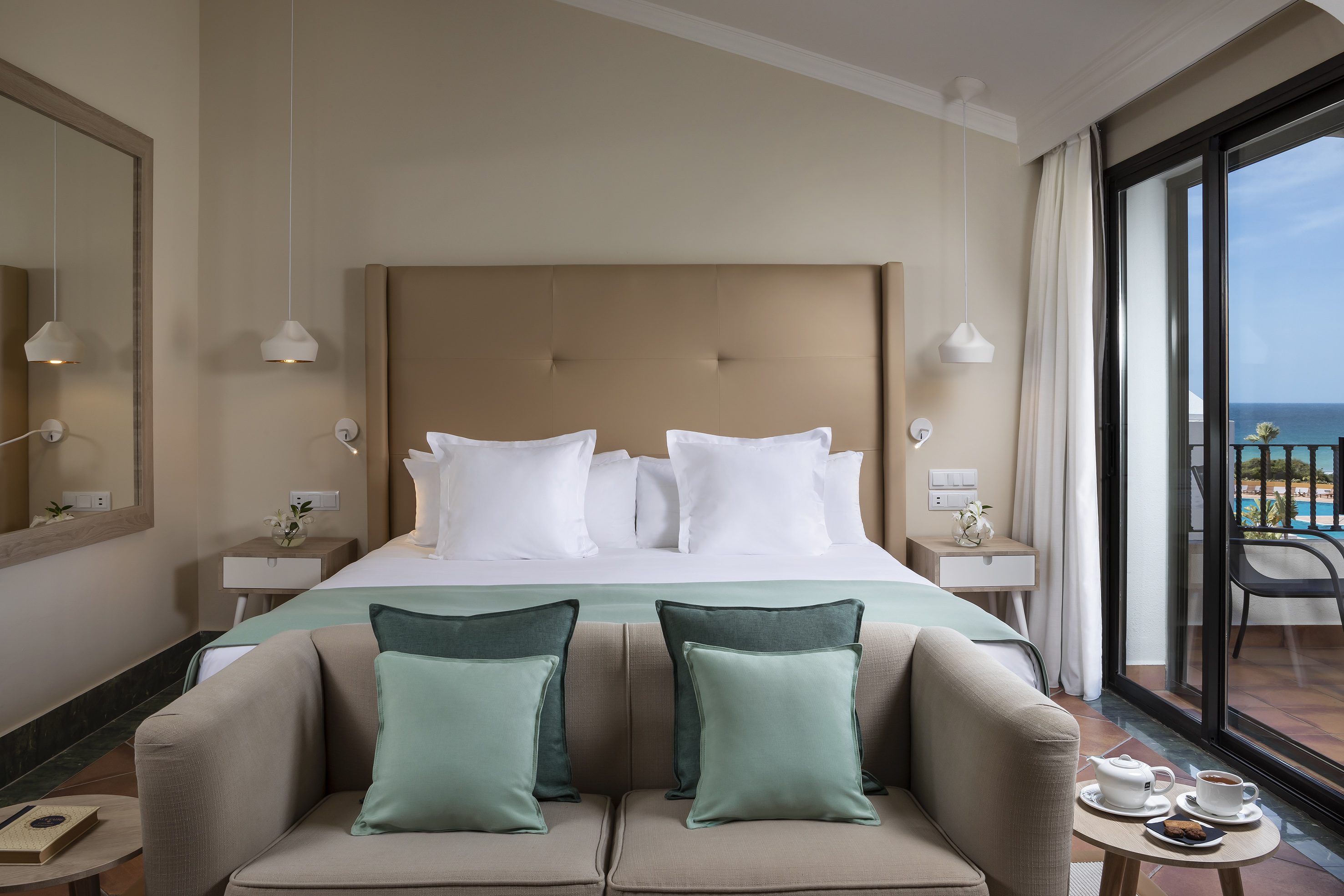Luxurious hotel bedroom with a sea view balcony and stylish decor.