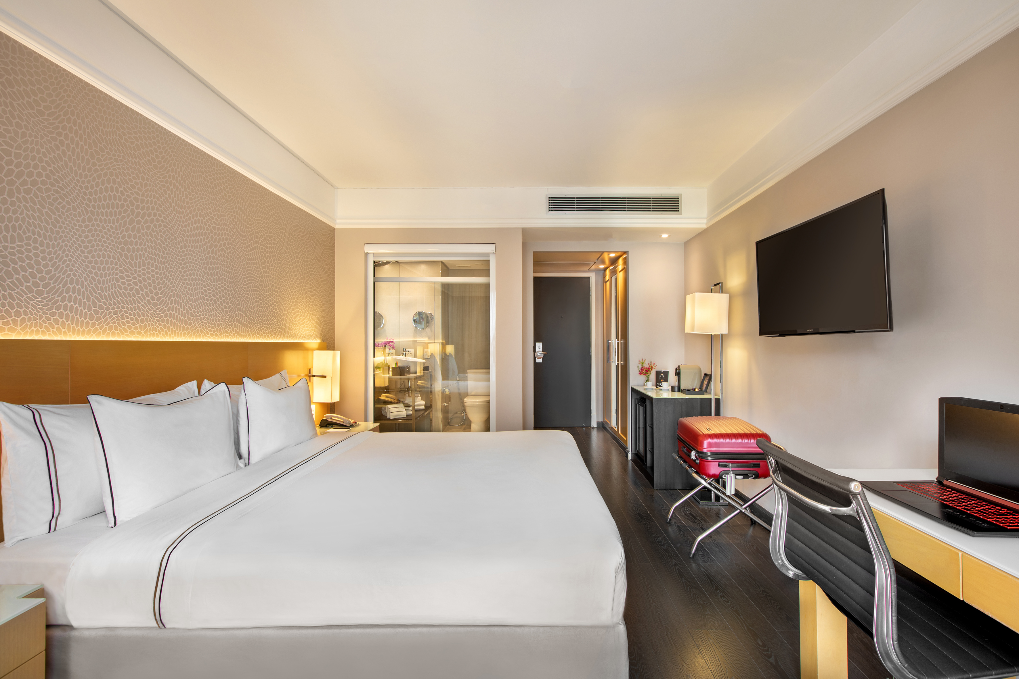 Modern hotel room with king bed, desk, flat-screen TV, and contemporary design.