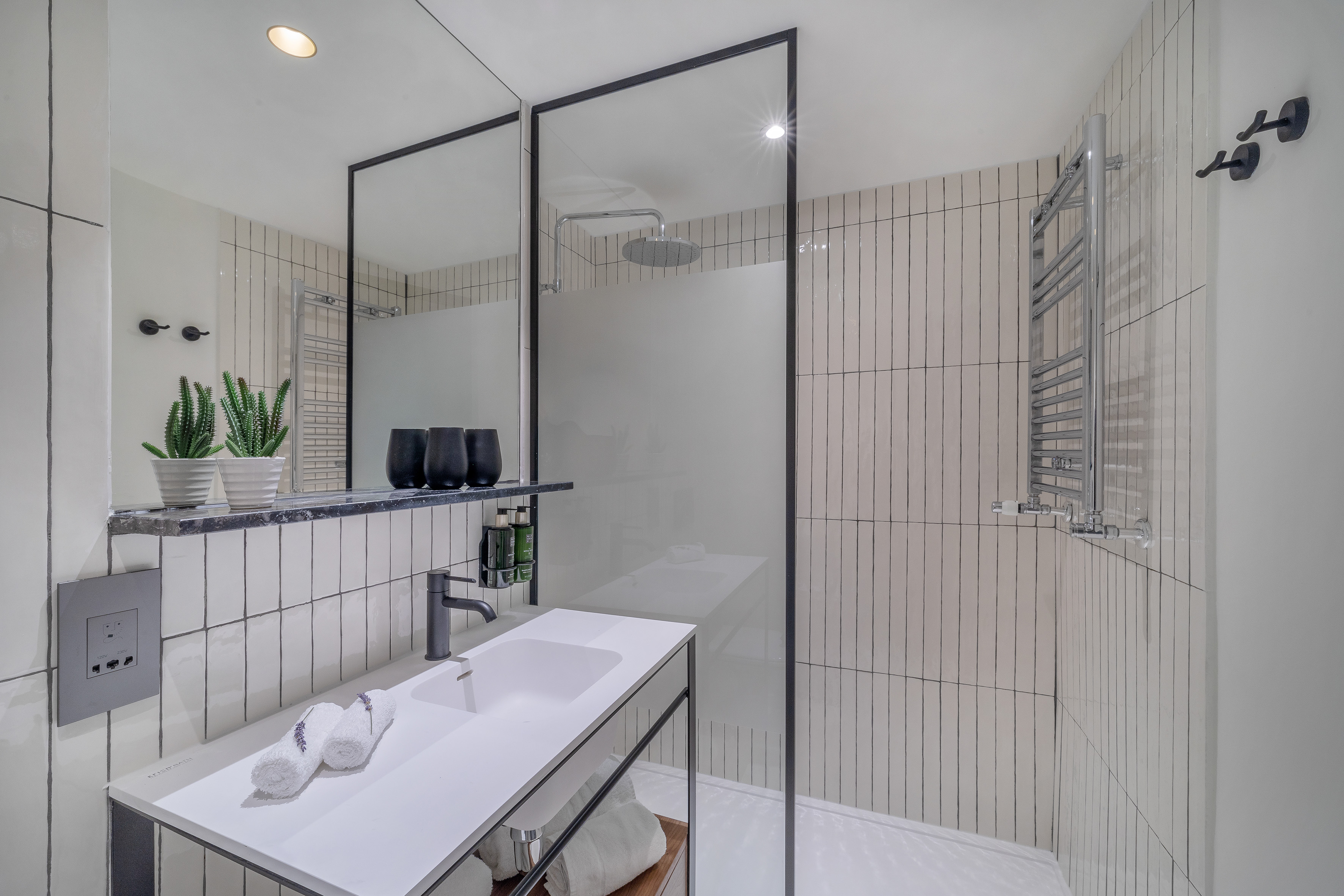 Modern white bathroom with vertical tiles, walk-in shower, and vanity.