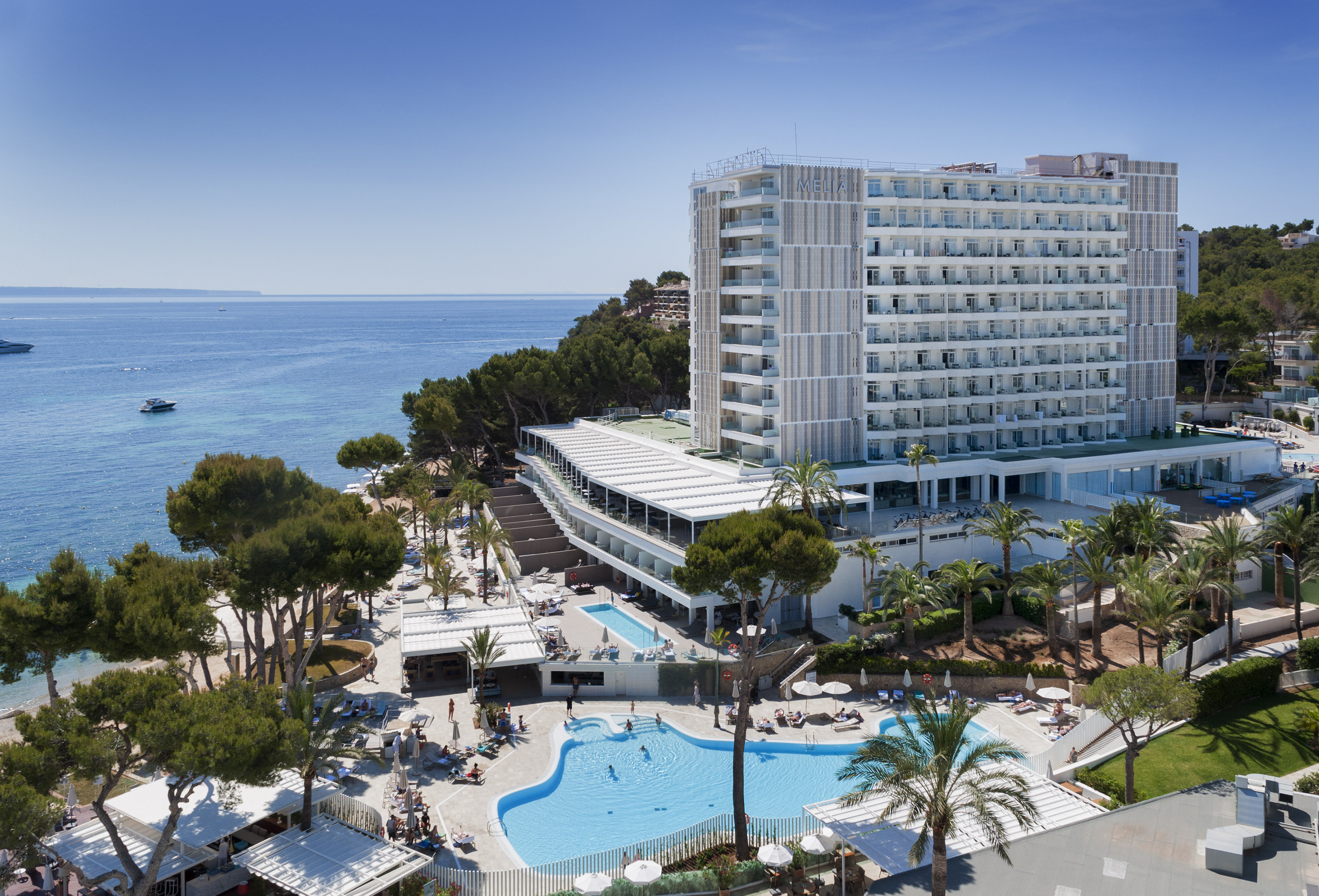 Aerial view of Melia hotel resort by ocean, featuring pools, beach, and boats.