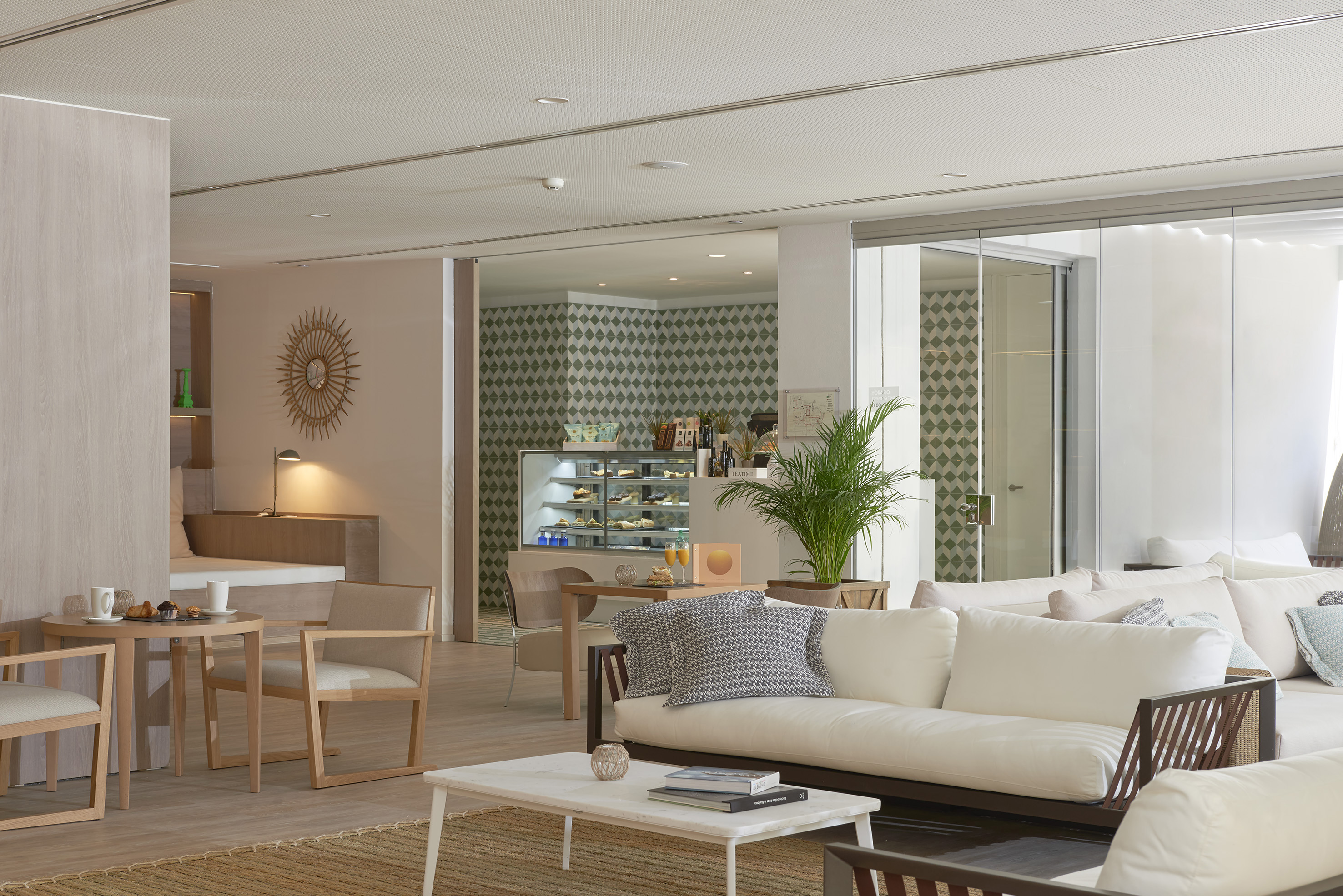 Modern lounge with white sofas, cafe counter, and light wood seating.