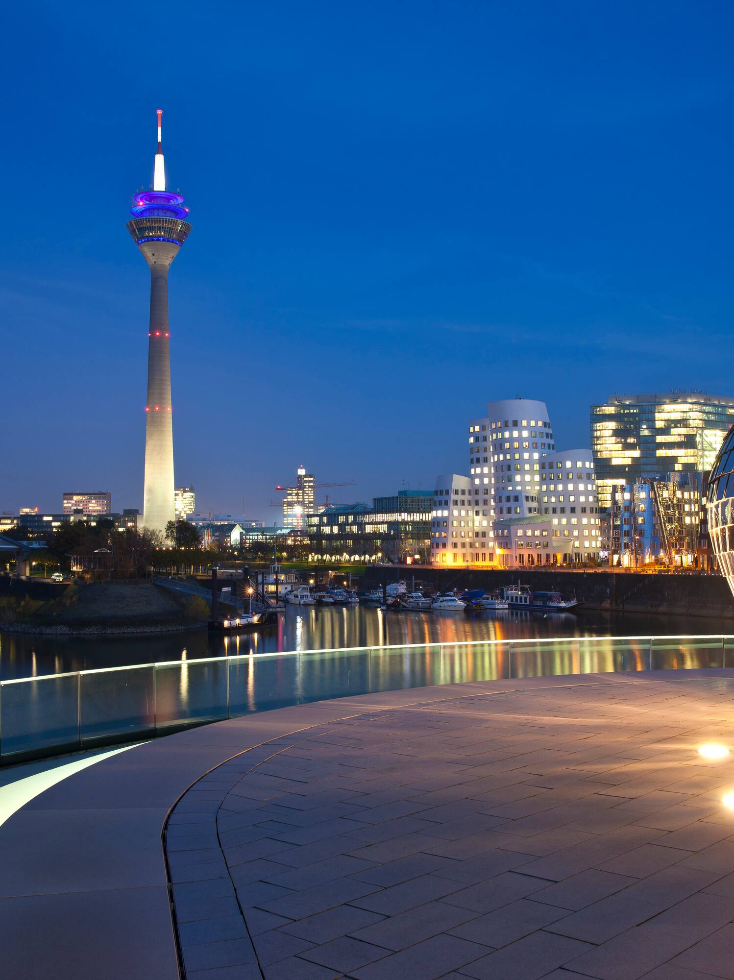 Düsseldorf Media Harbour skyline at night with Rheinturm and river reflections.
