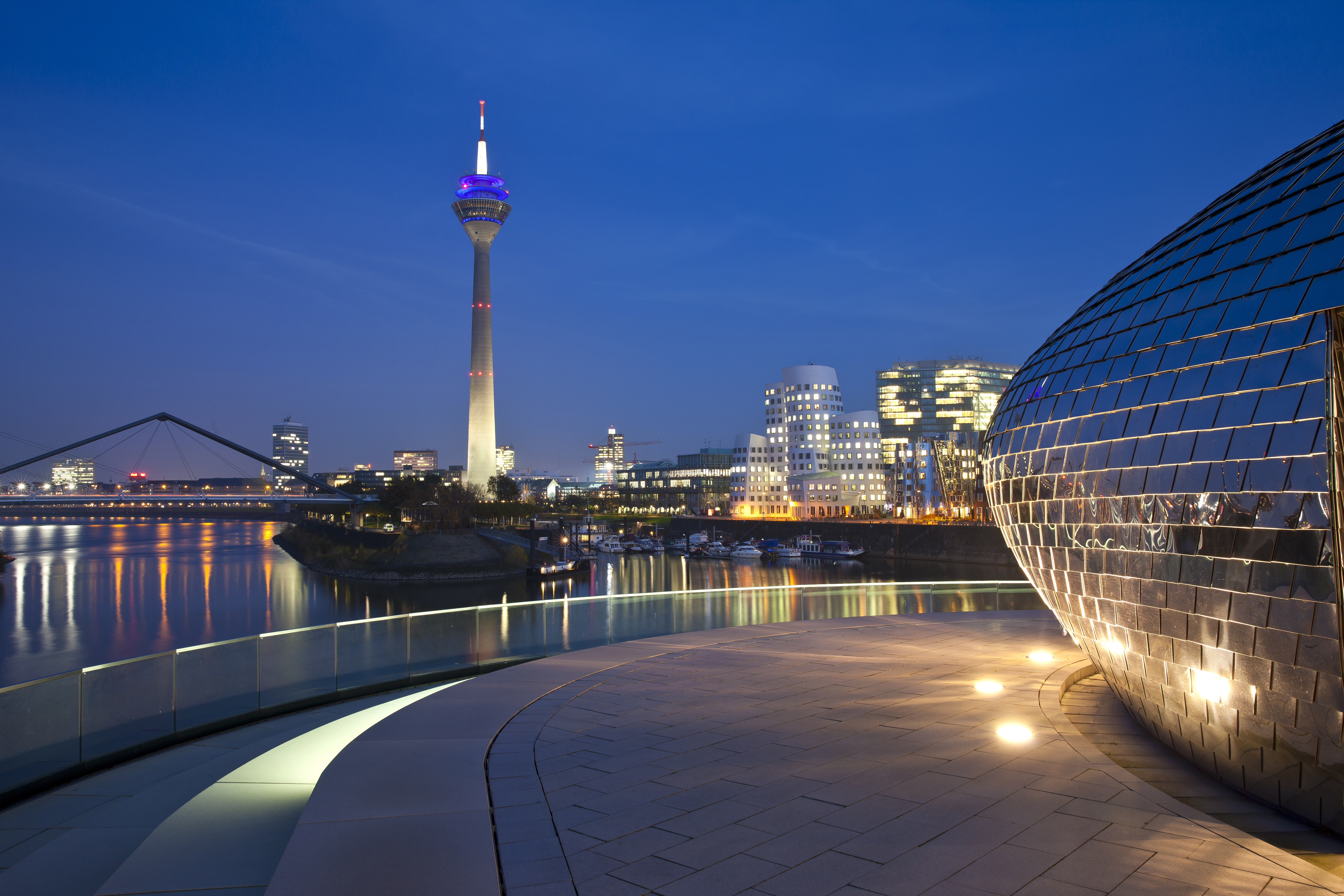 Düsseldorf Media Harbour skyline at night with Rheinturm and river reflections.