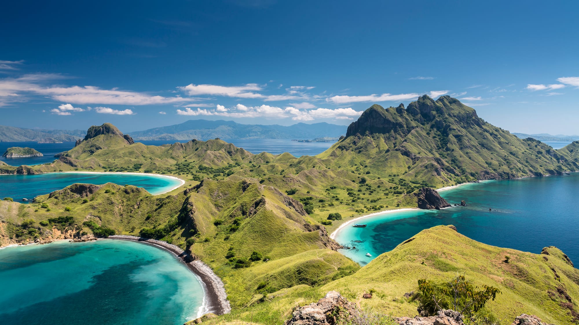 a green hills with islands and blue water