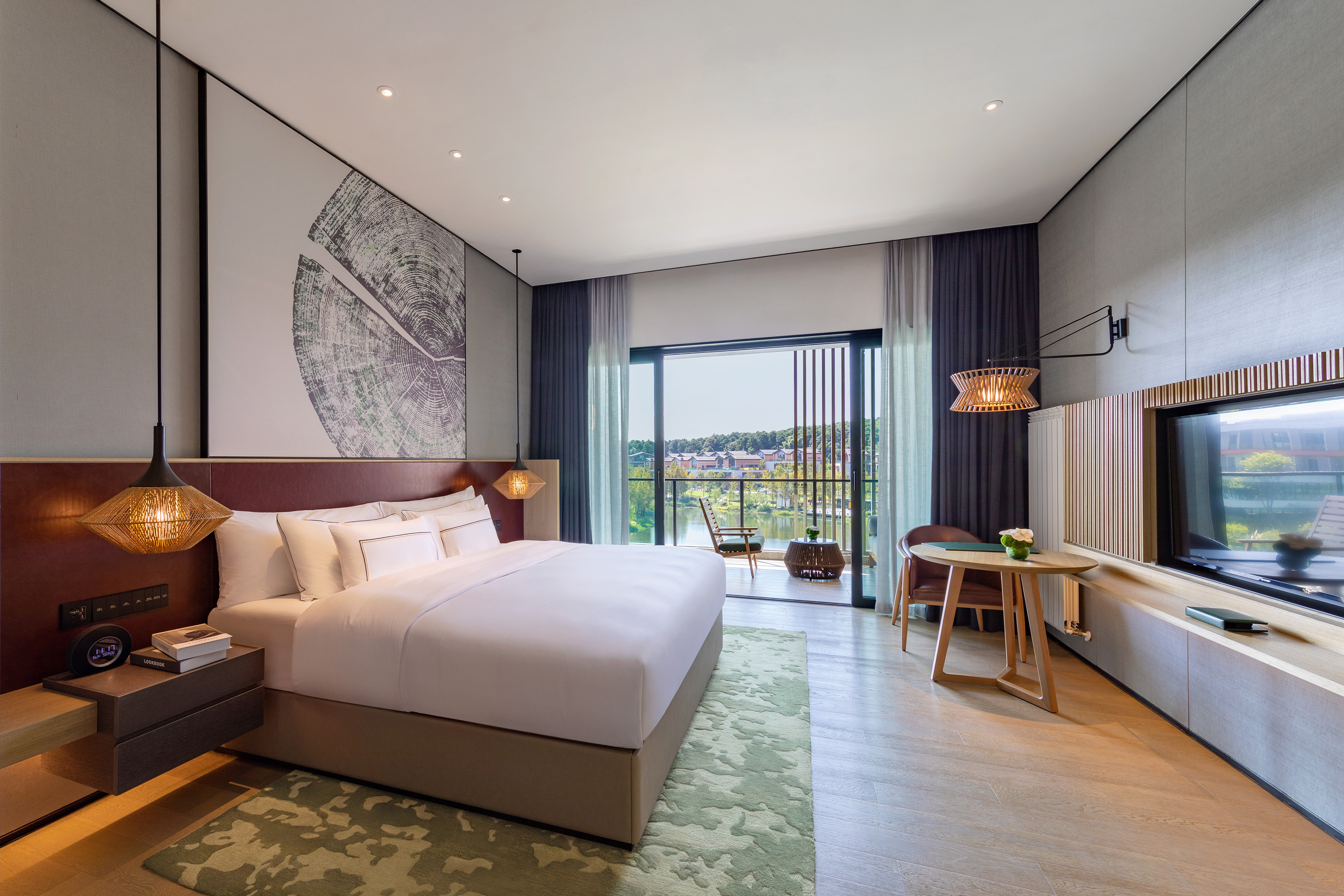Luxury hotel bedroom with balcony overlooking lake, modern decor.