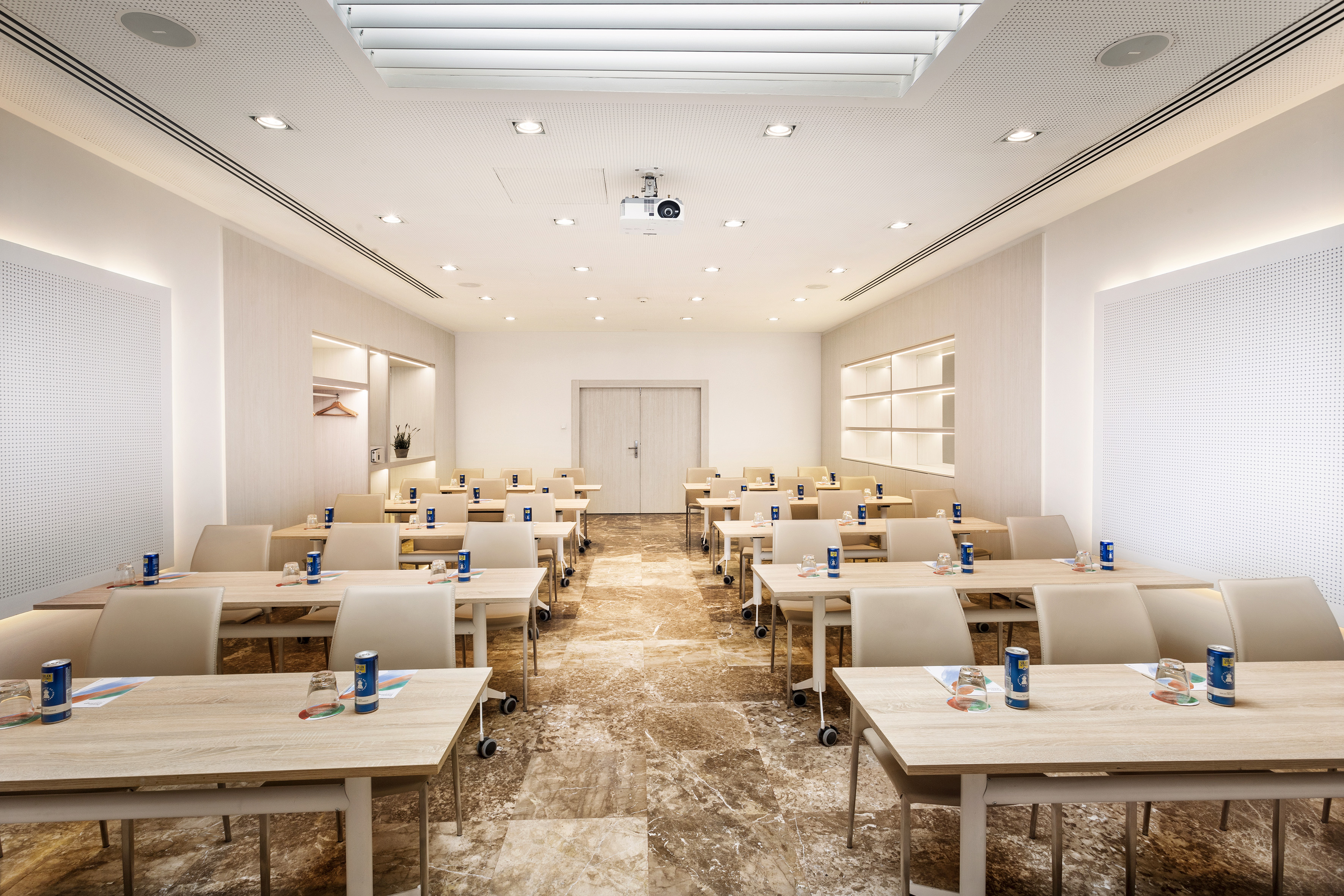 Modern corporate meeting room with tables, chairs, and a ceiling projector.