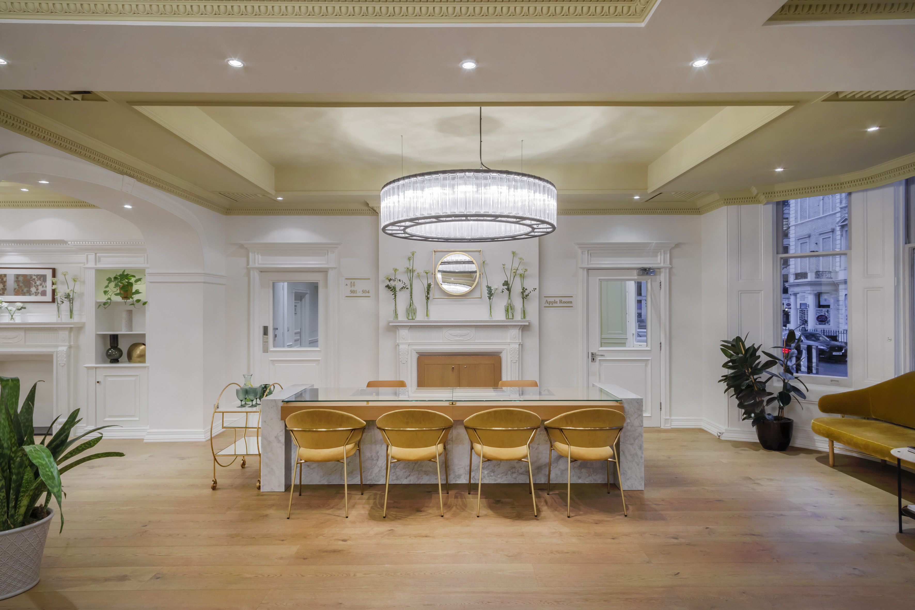 Luxurious hotel lobby with marble reception desk, gold chairs, and chandelier.