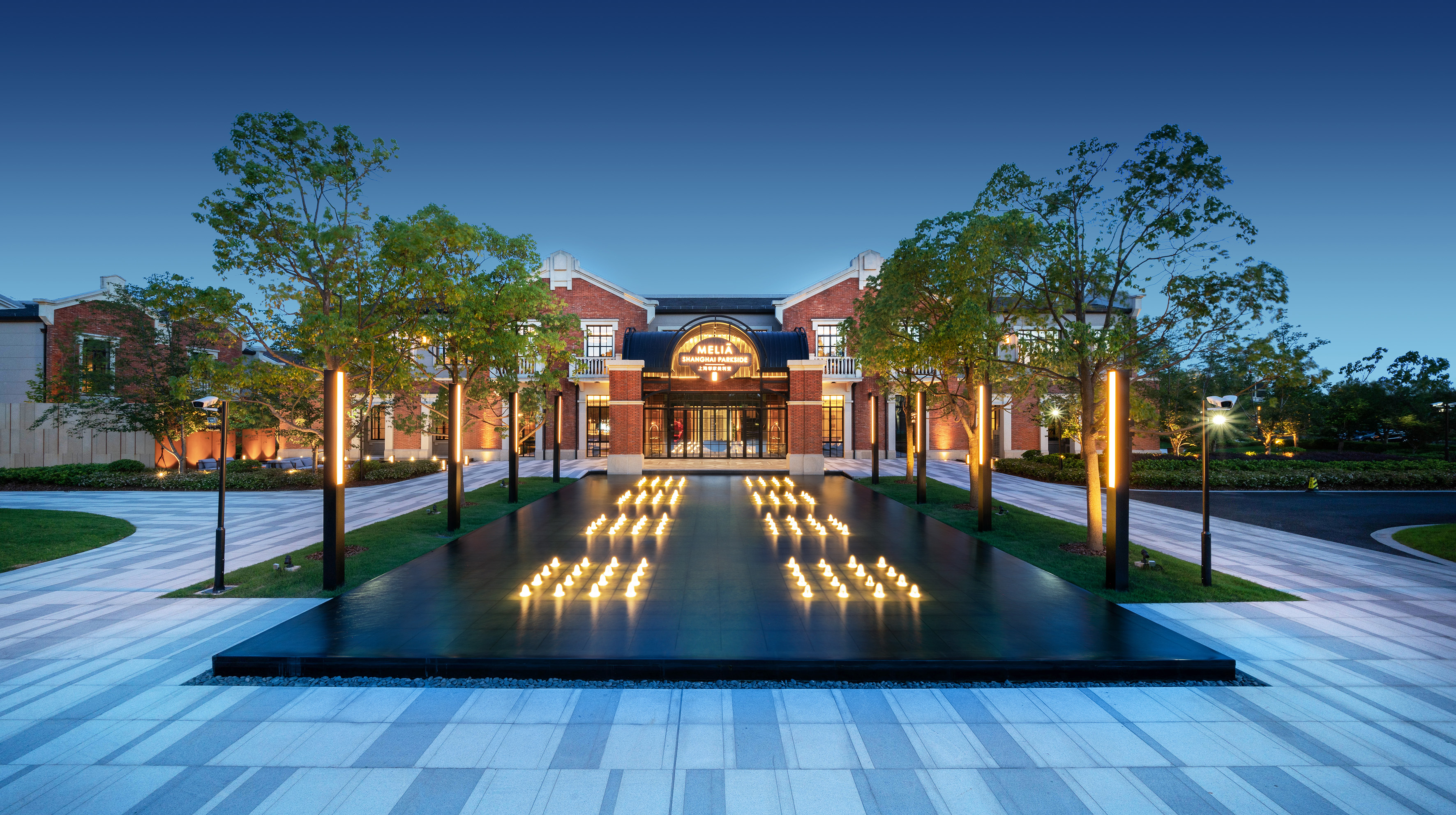 Meliá Shanghai Parkside hotel exterior at dusk with illuminated water feature.