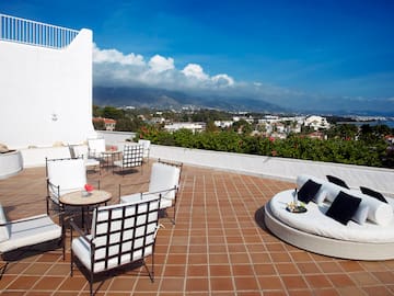 a patio with white furniture and a view of the city