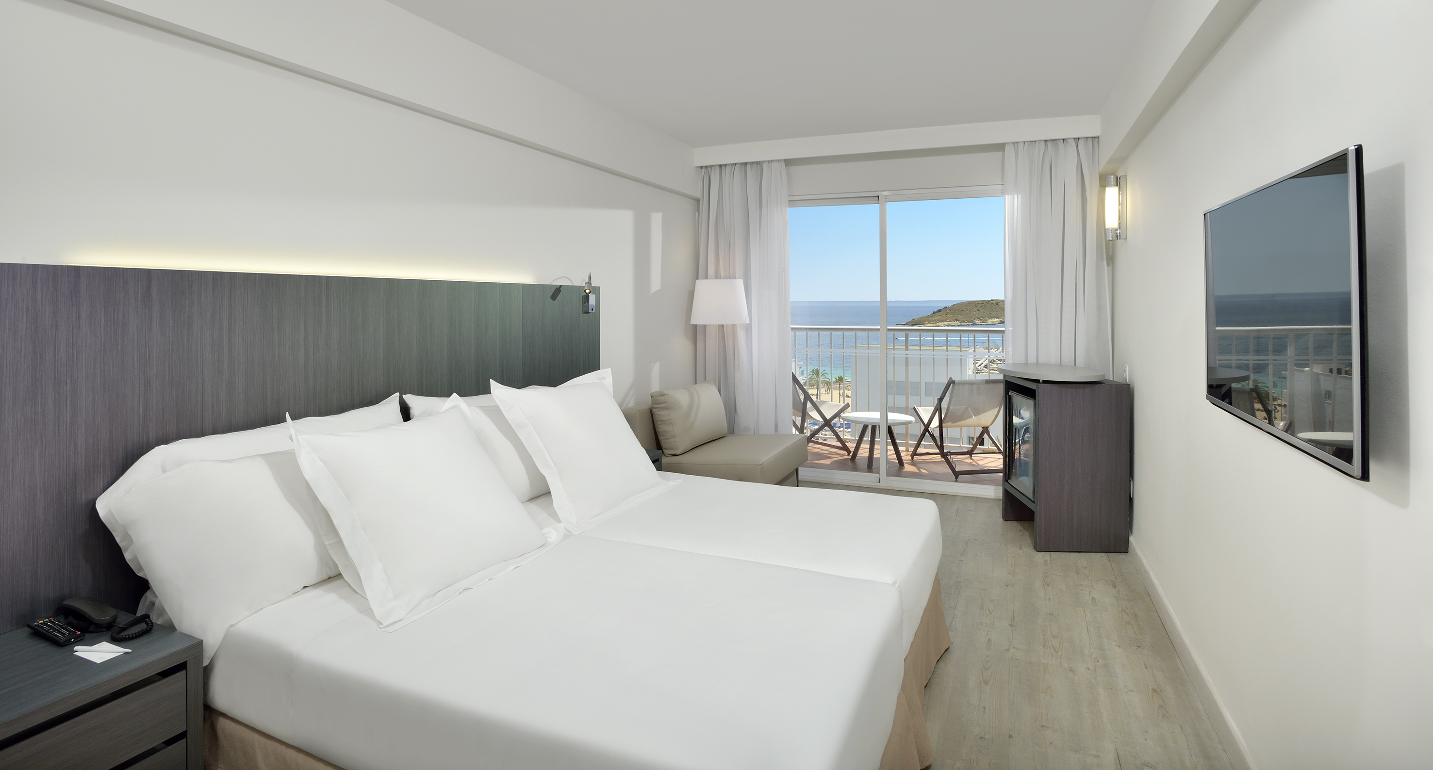a room with a large bed and a balcony overlooking the ocean