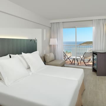 a room with a large bed and a balcony overlooking the ocean