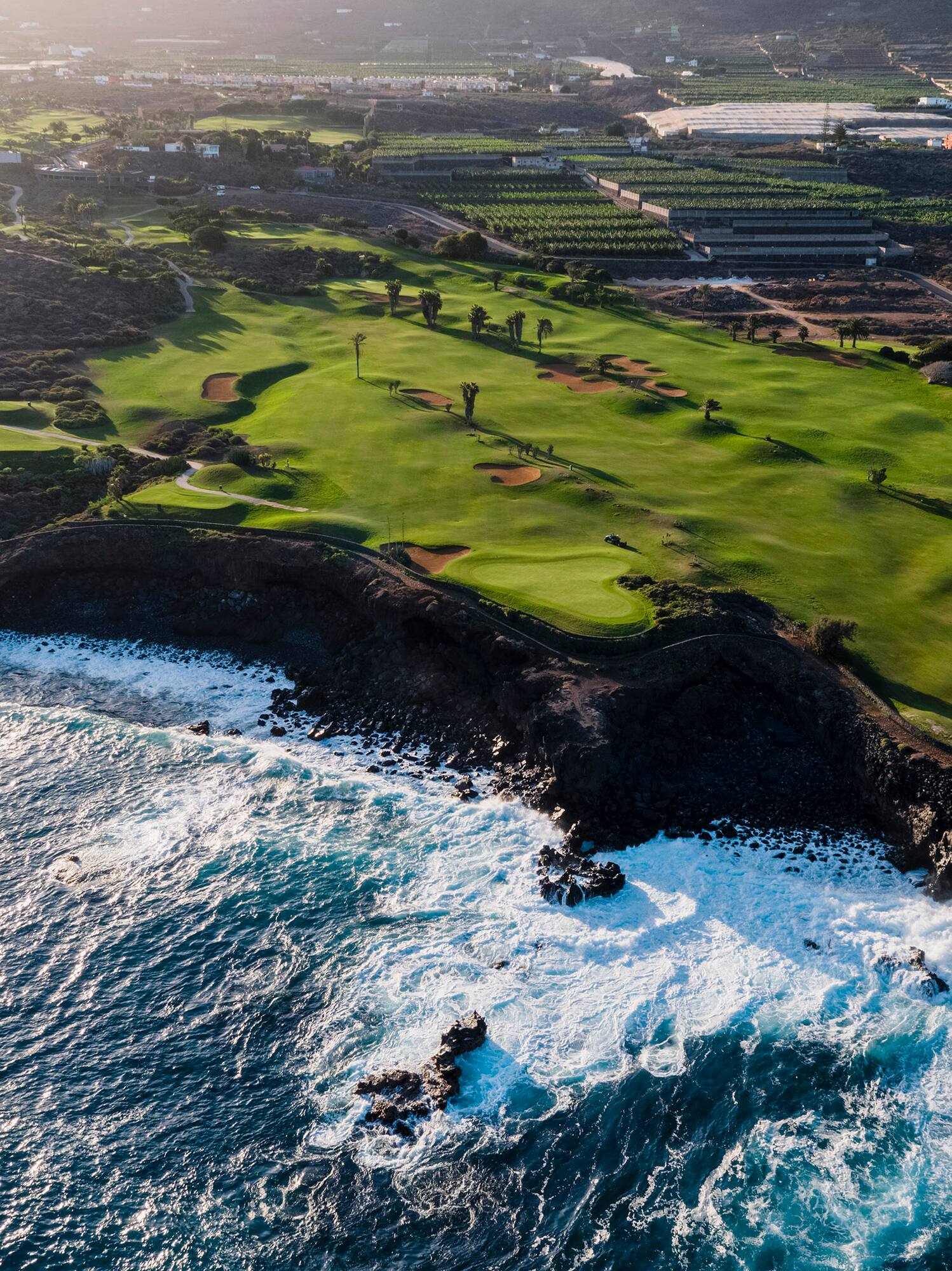 a golf course with waves crashing on the shore