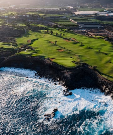 a golf course with waves crashing on the shore