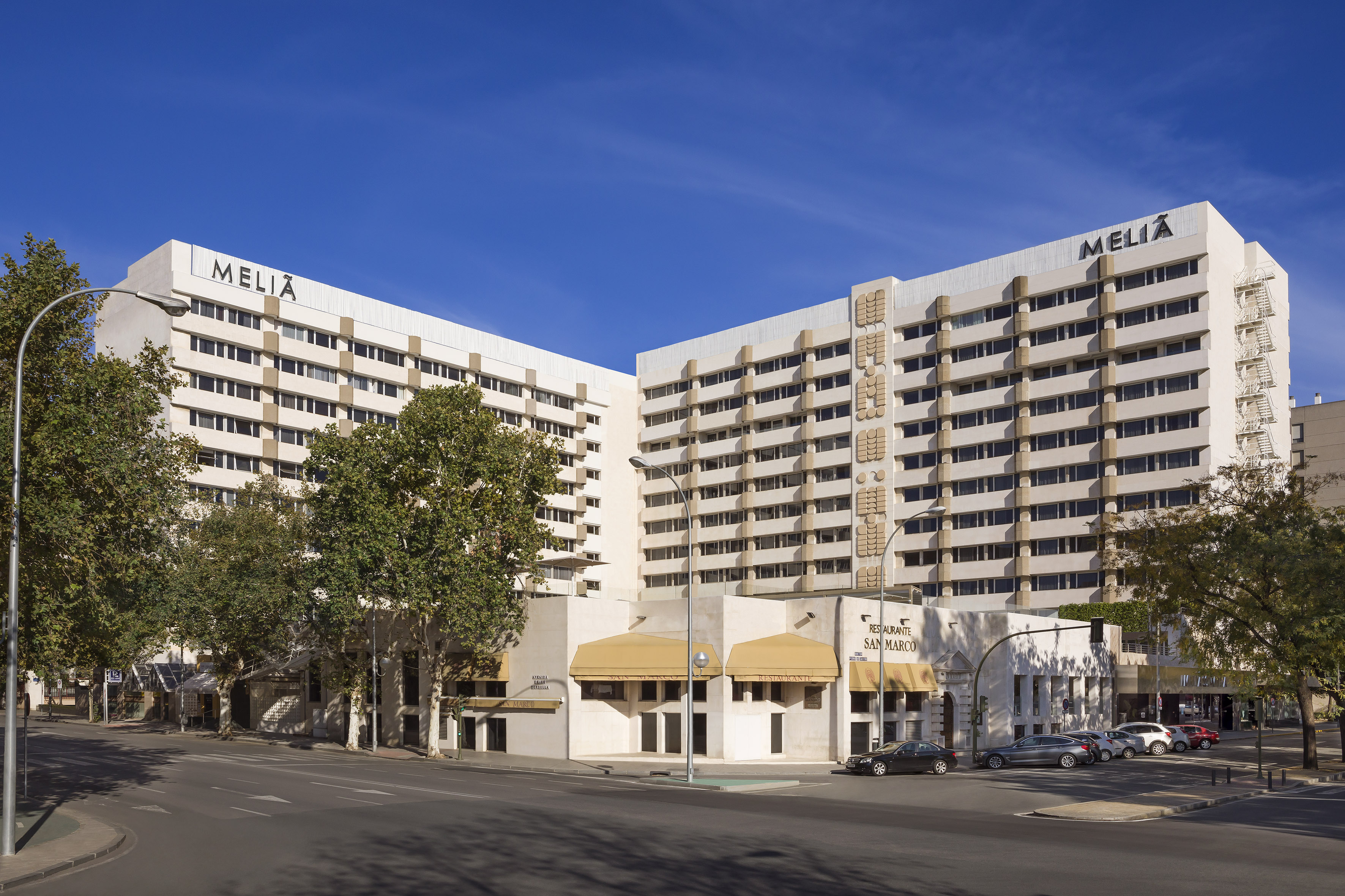 Melia Hotel building, "RESTAURANTE SAN MARCO", urban street, cars, and trees.