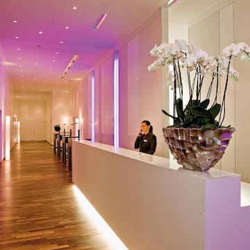 a long hallway with a white wall and a woman standing behind a white counter