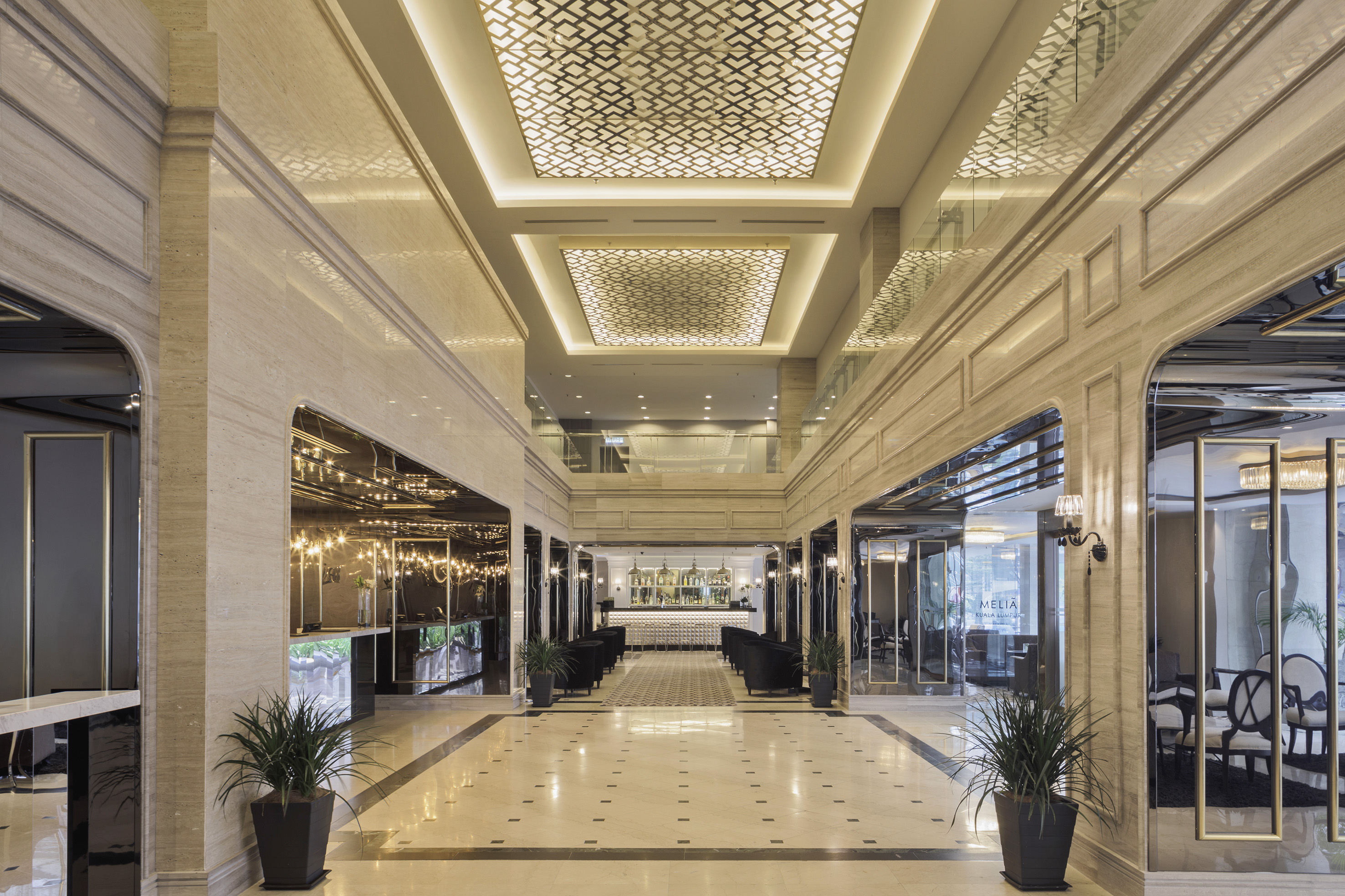 Melia Kuala Lumpur hotel lobby, elegant marble, patterned ceilings, and bar.