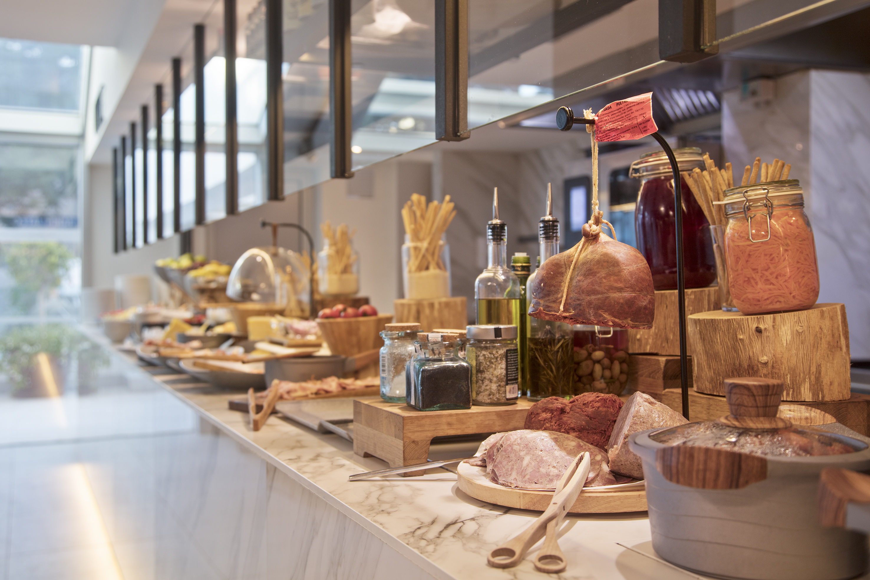 Savory buffet spread with deli meats, artisan bread, oils, and pickled foods.