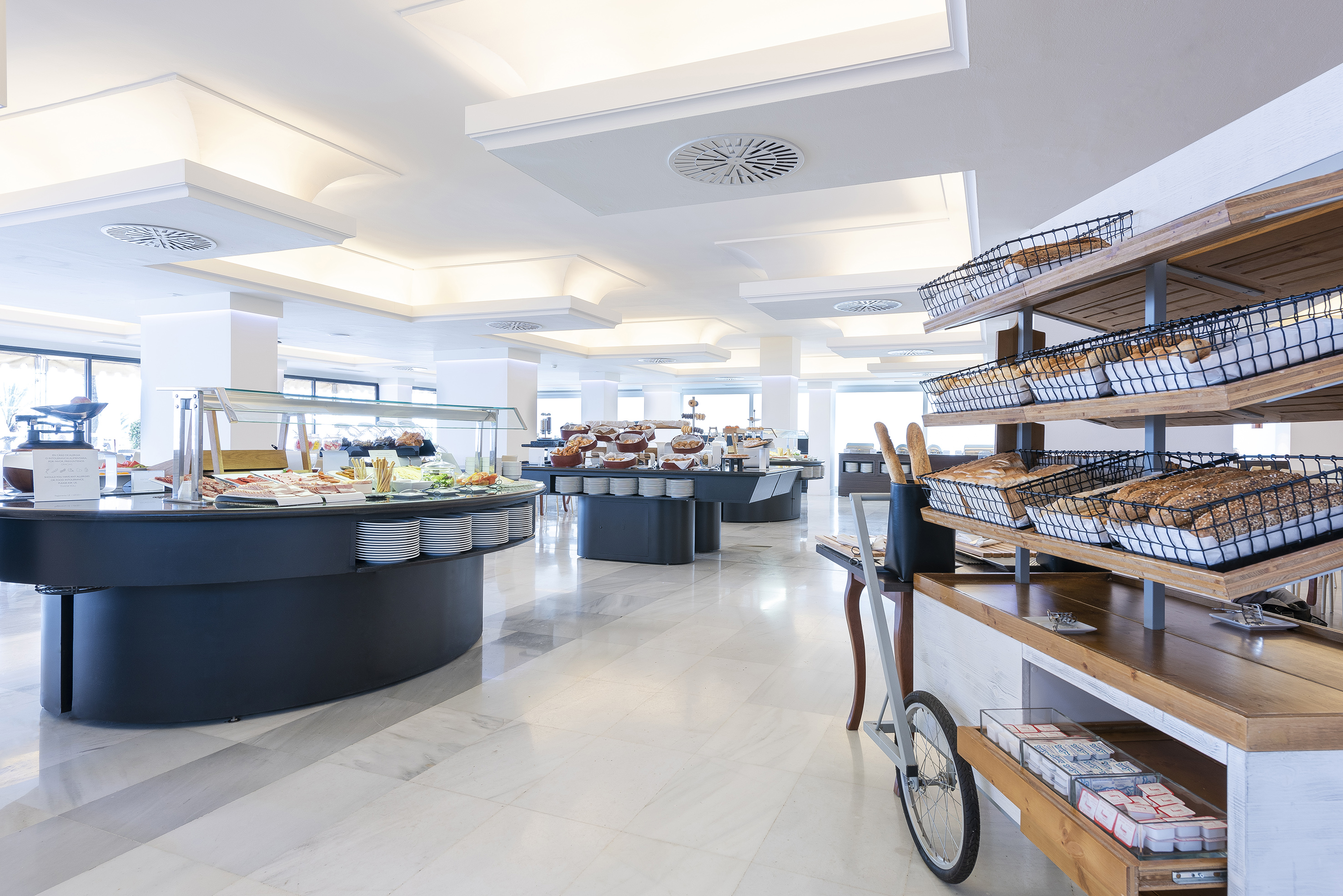 Bright hotel buffet featuring diverse food stations, fresh bread, and pastries.