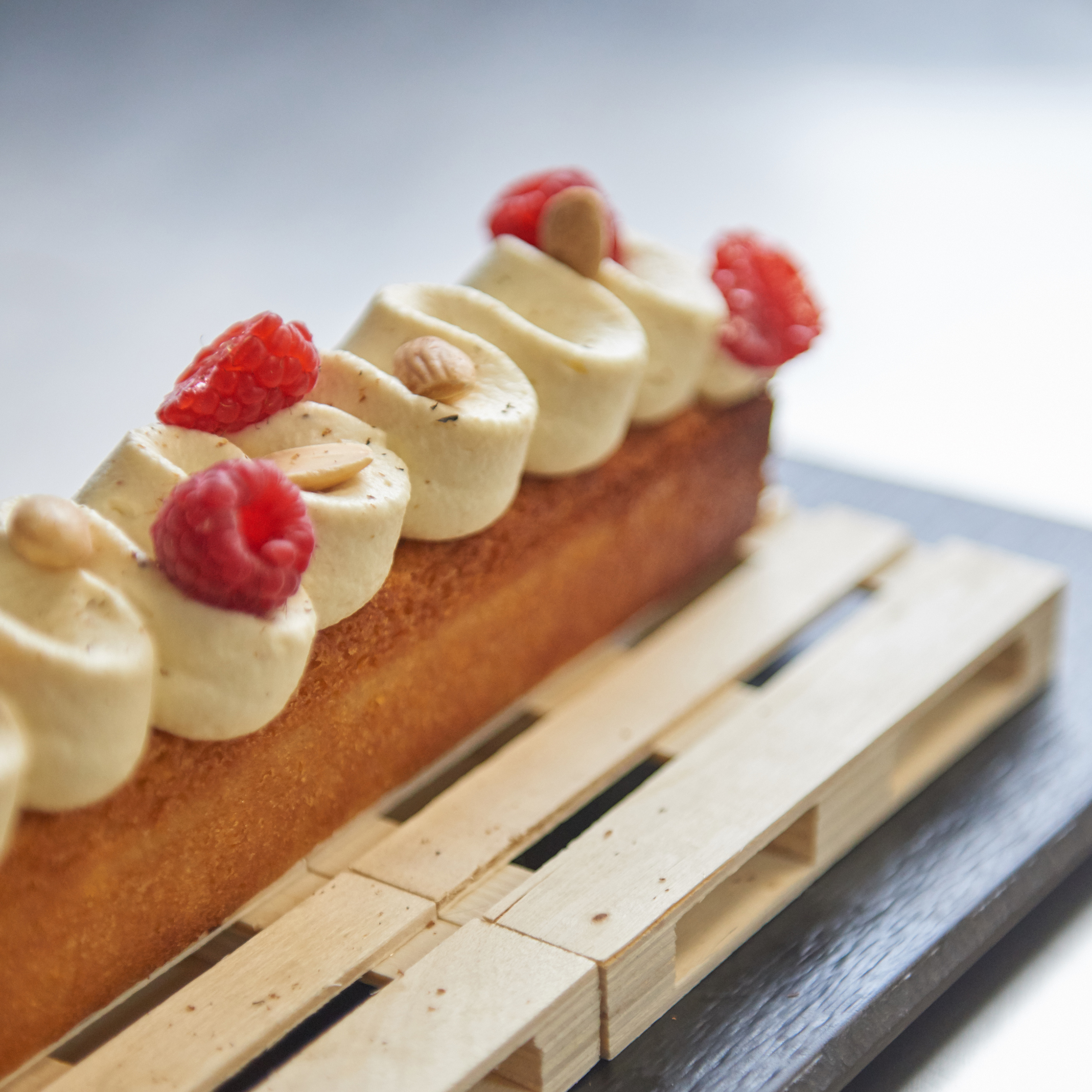 Raspberry dessert bar with cream, almonds, on a wooden pallet.